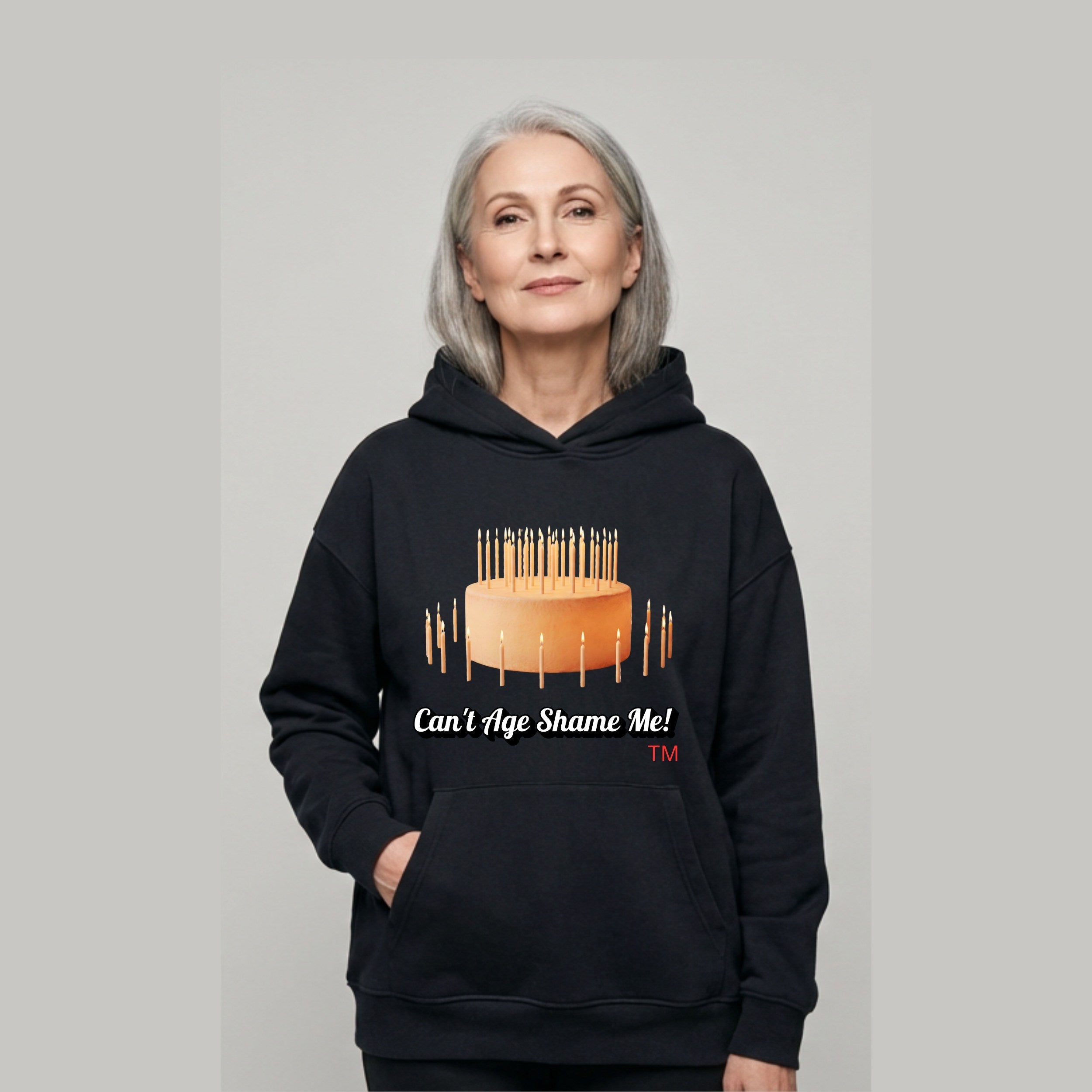 a.	"Woman wearing Can't Age Shame Me! unisex hoodie with visual of birthday cake with lots of candles