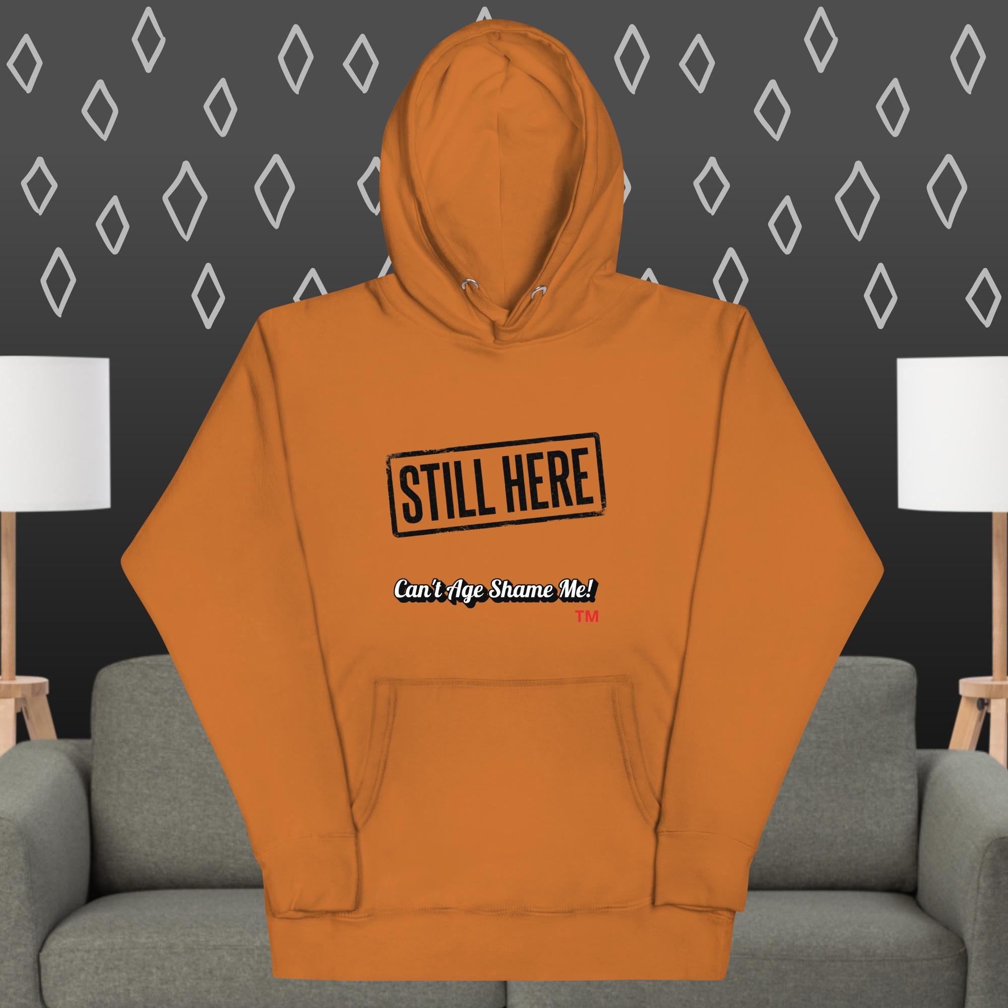 Adobe hoodie with text on a gray couch and patterned wall background