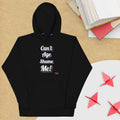 Black hoodie with 'Can't Age Shame Me' text on a wooden surface with books and paper cranes.