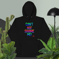 Black hoodie with colorful text 'CAN'T AGE SHAME ME!' in a room with plants and a lamp.