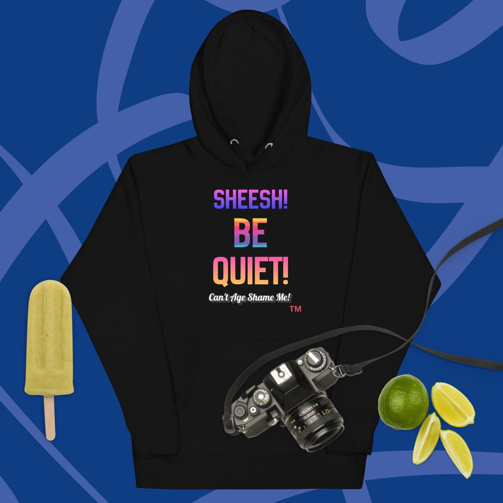 Black hoodie with colorful text: Sheesh! Be Quiet! 'Can't Age Shame Me!
 on a blue background with camera, popsicle, and limes.


