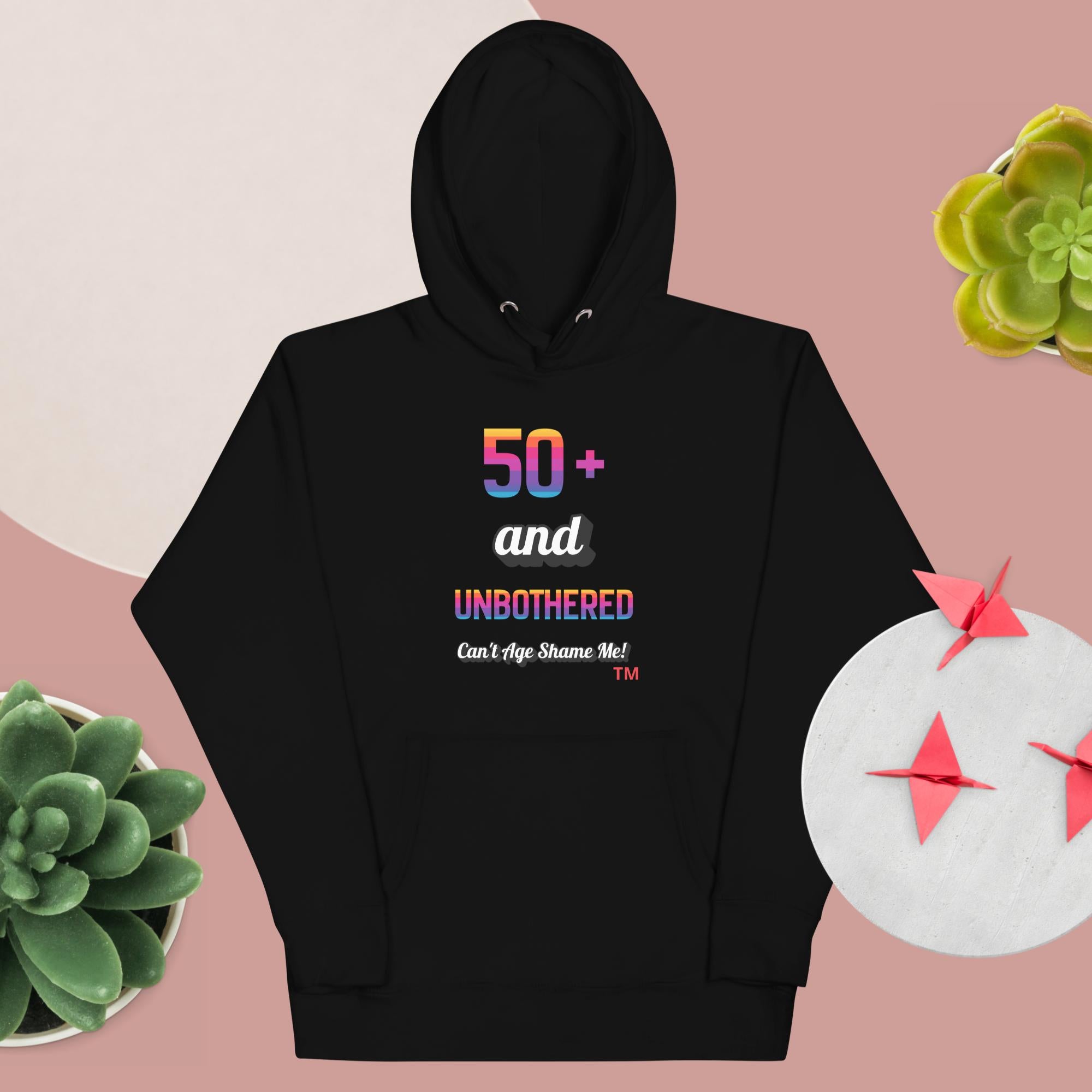 Black hoodie with colorful text design on a pink background with decorative elements.