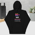Black hoodie with colorful text design on a gray surface with a plant and box in the background