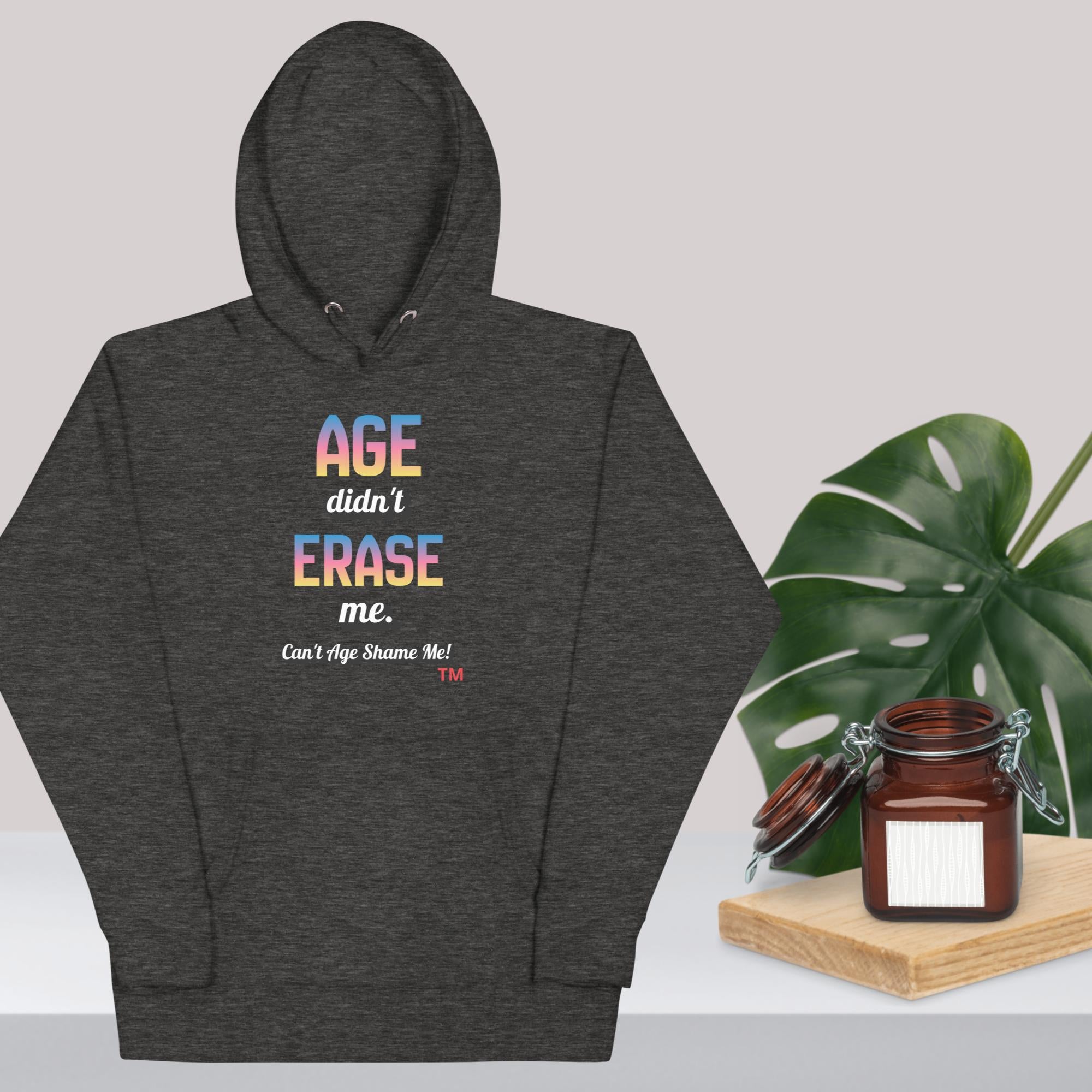 Charcoal Heather hoodie with colorful text design on a light gray background with a plant and jar.