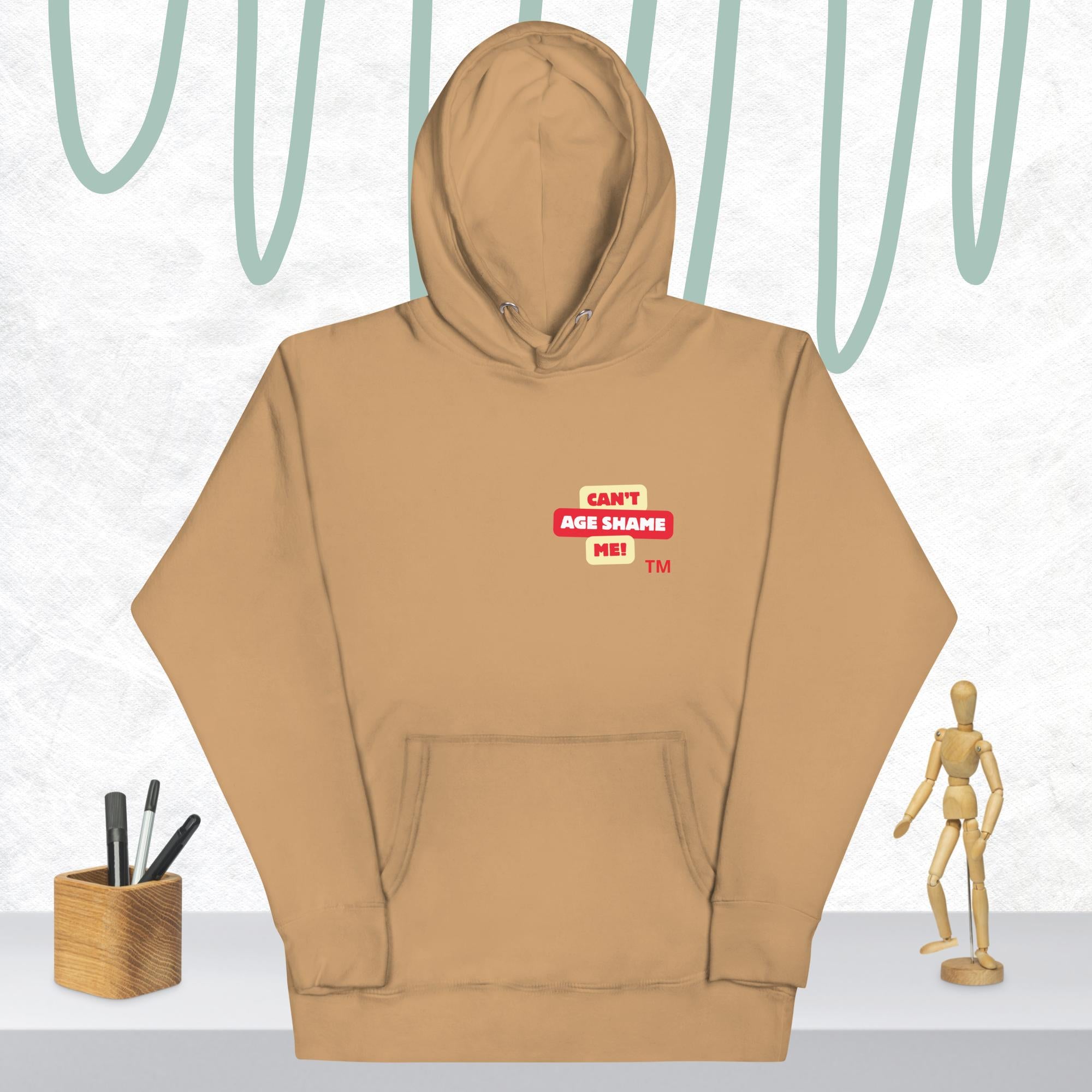  Khaki hoodie with a red and white logo text 'CAN'T AGE SHAME ME! on a light gray background