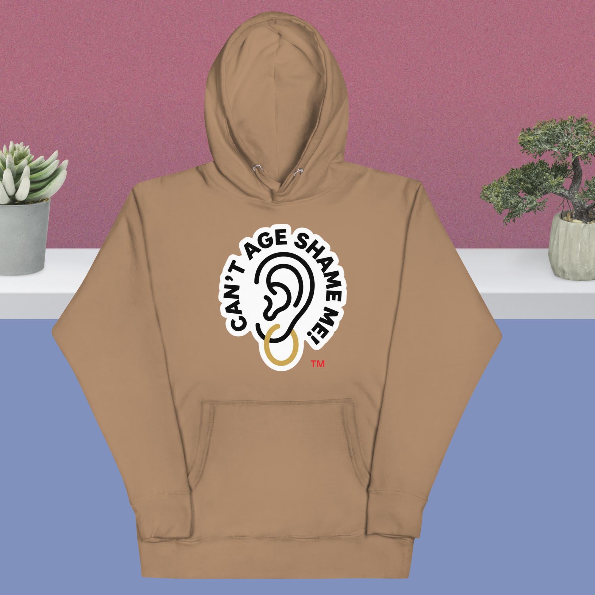 Latte hoodie with 'Can't Age Shame Me!' graphic on a blue and pink gradient background