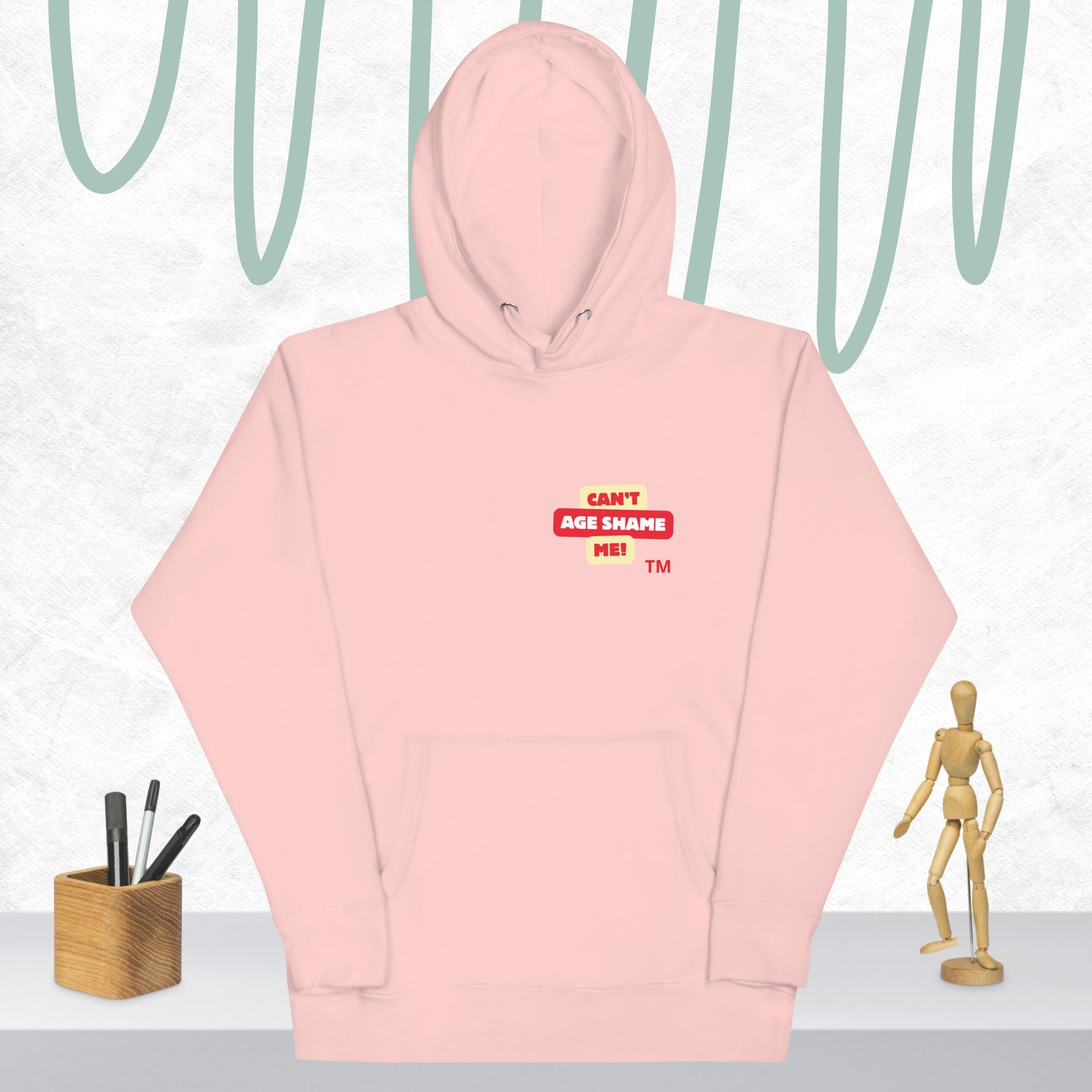 Light pink hoodie with a red and white logo text 'CAN'T AGE SHAME ME! on a light gray background