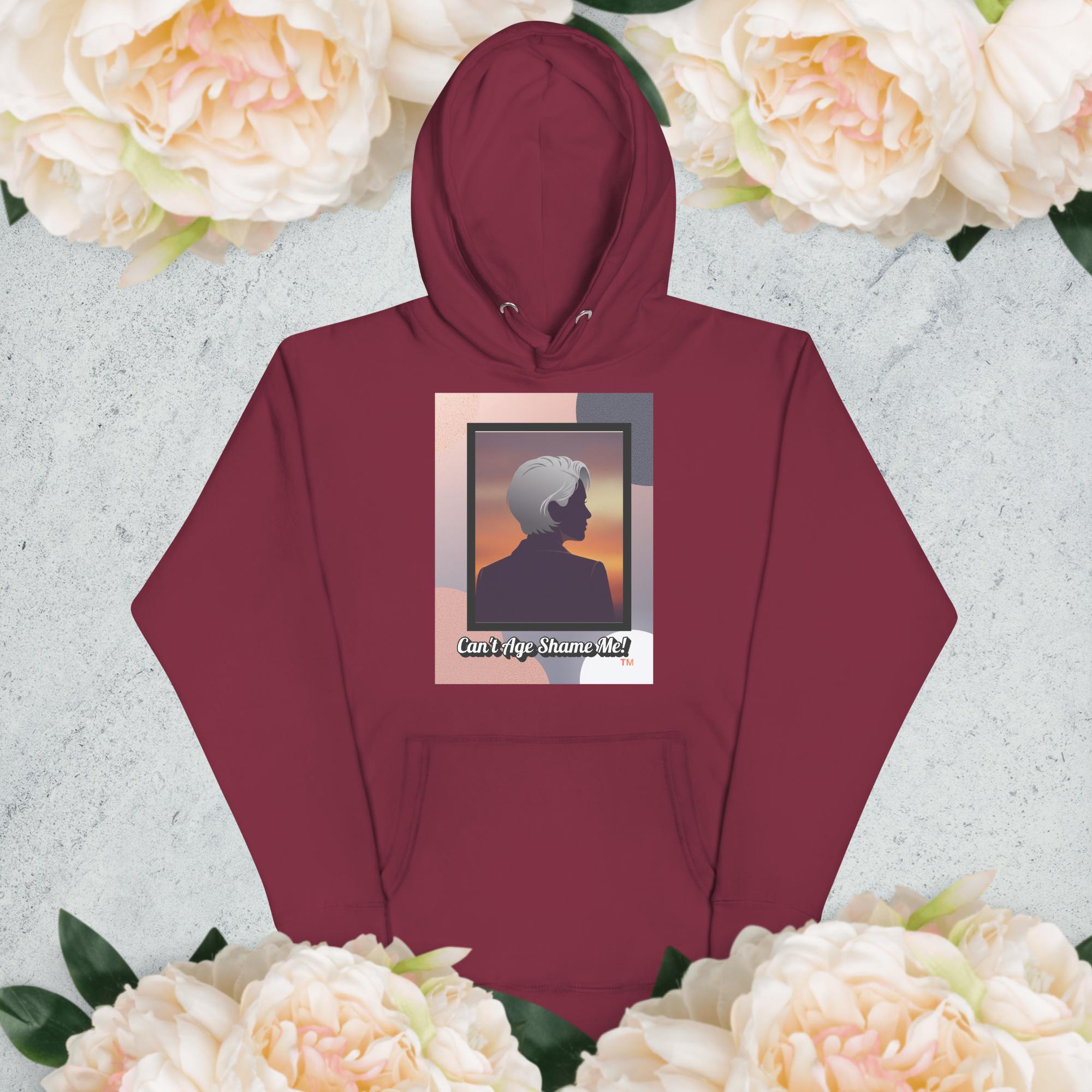 Maroon hoodie with a graphic design of a woman with gray hair on a light gray background with flowers

