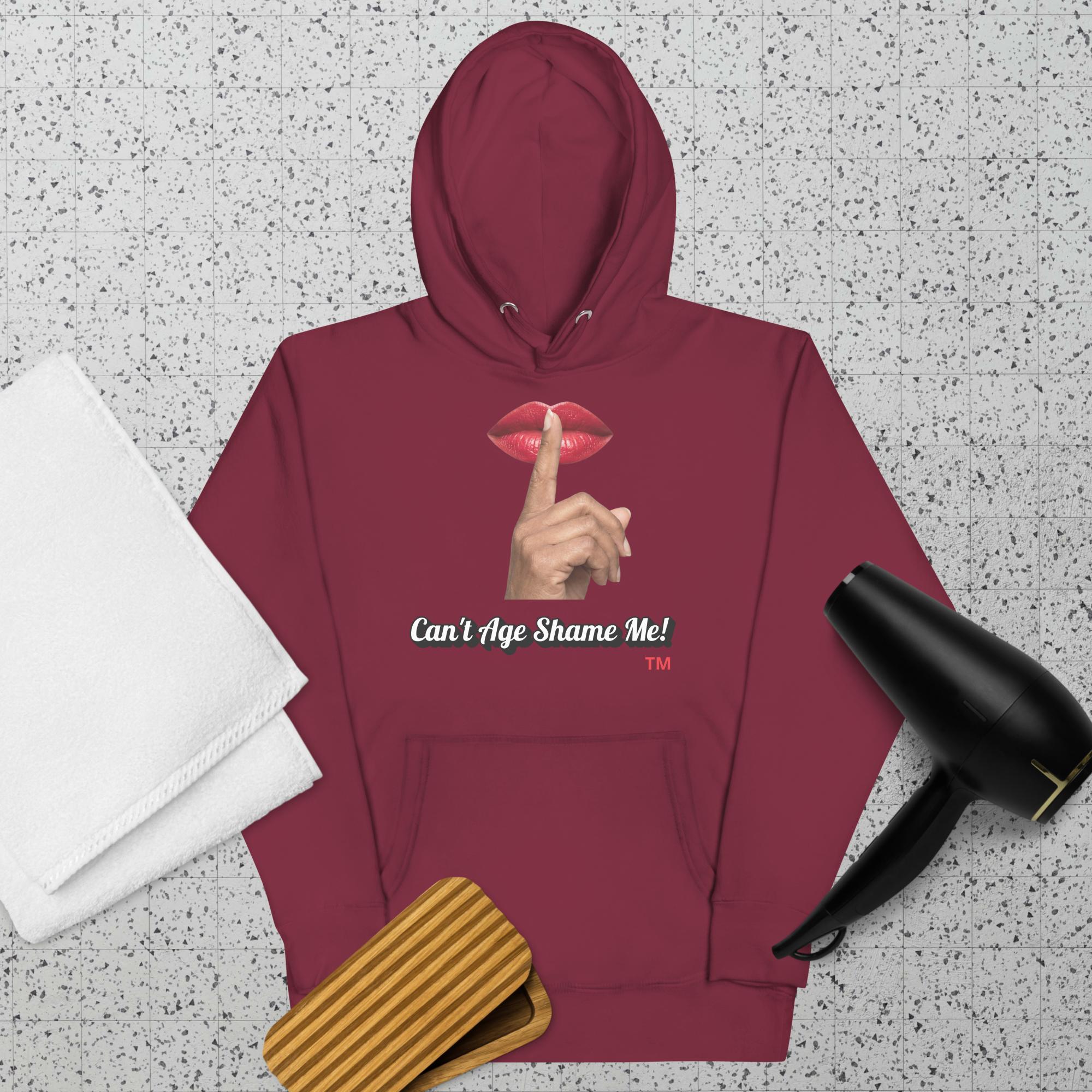 Maroon hoodie with a graphic design of lips and a finger on a textured surface