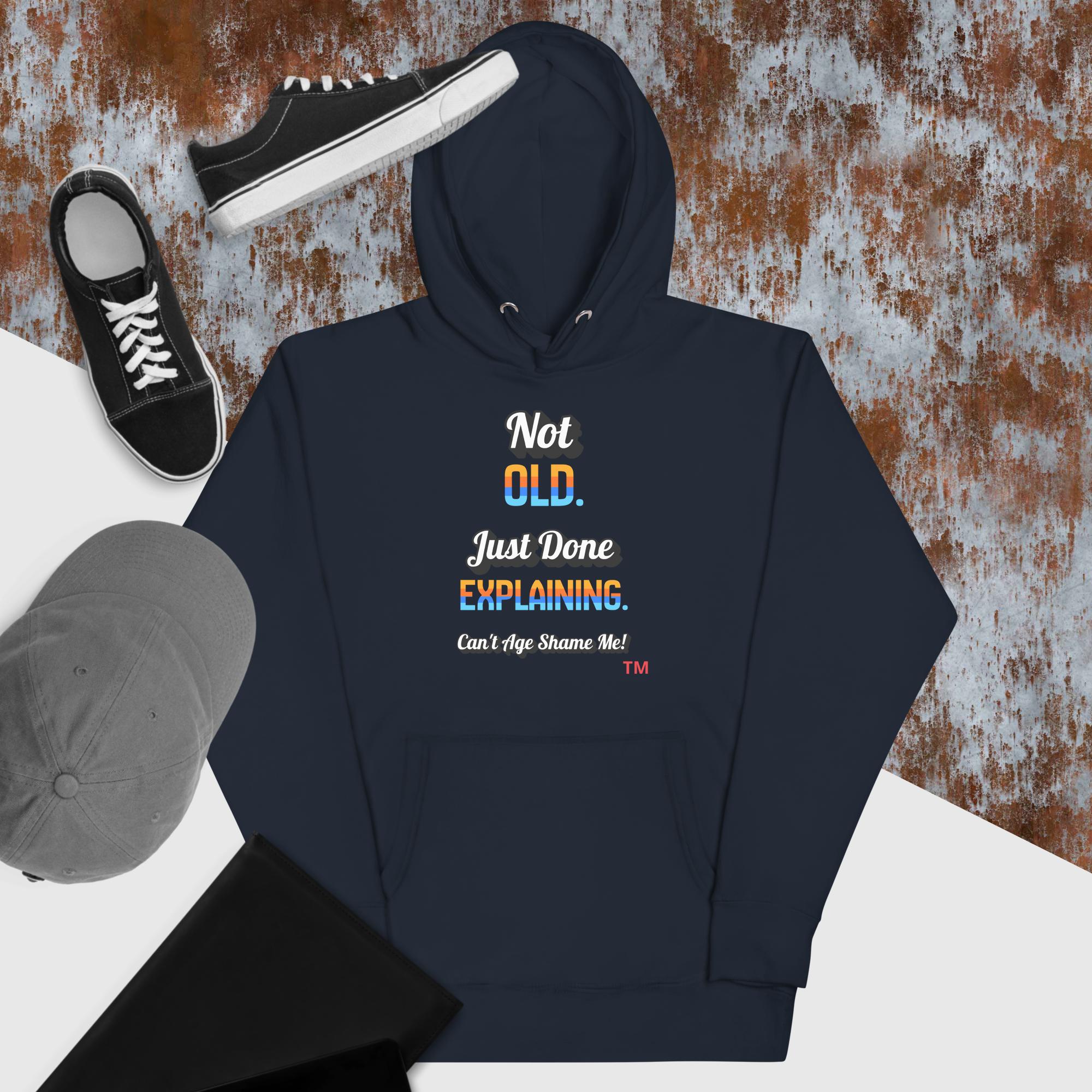 Navy hoodie with humorous text design, black sneakers, and gray cap on a textured surface.