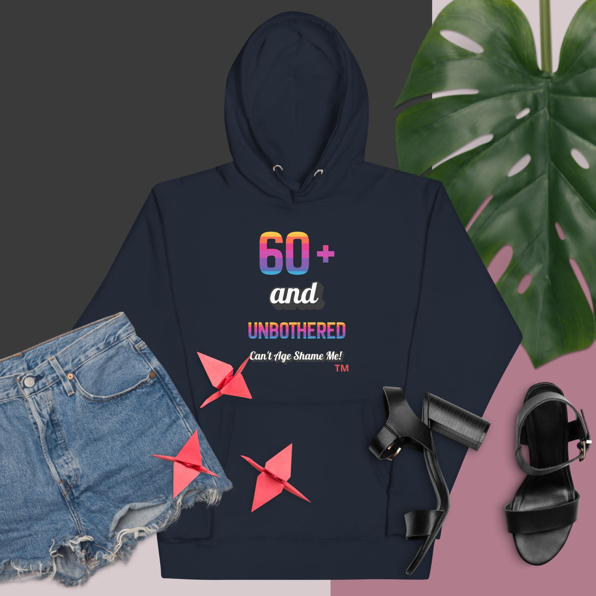Navy hoodie with colorful text and graphics, paired with denim shorts and black sandals on a dark background.