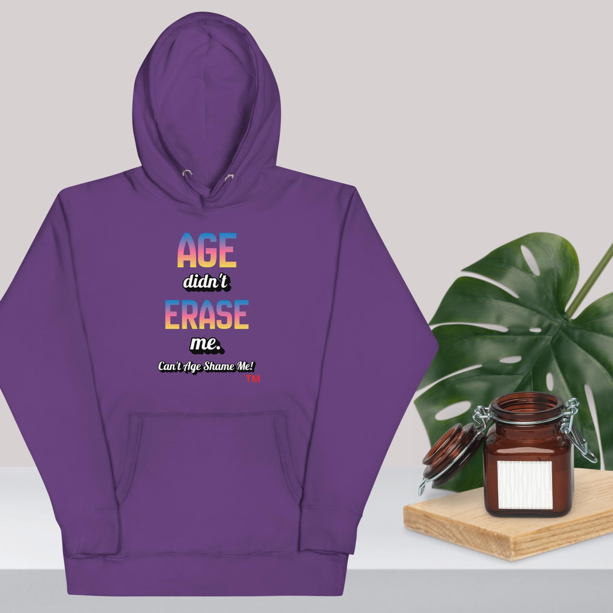 Purple hoodie with colorful text on a white background with a plant and jar.