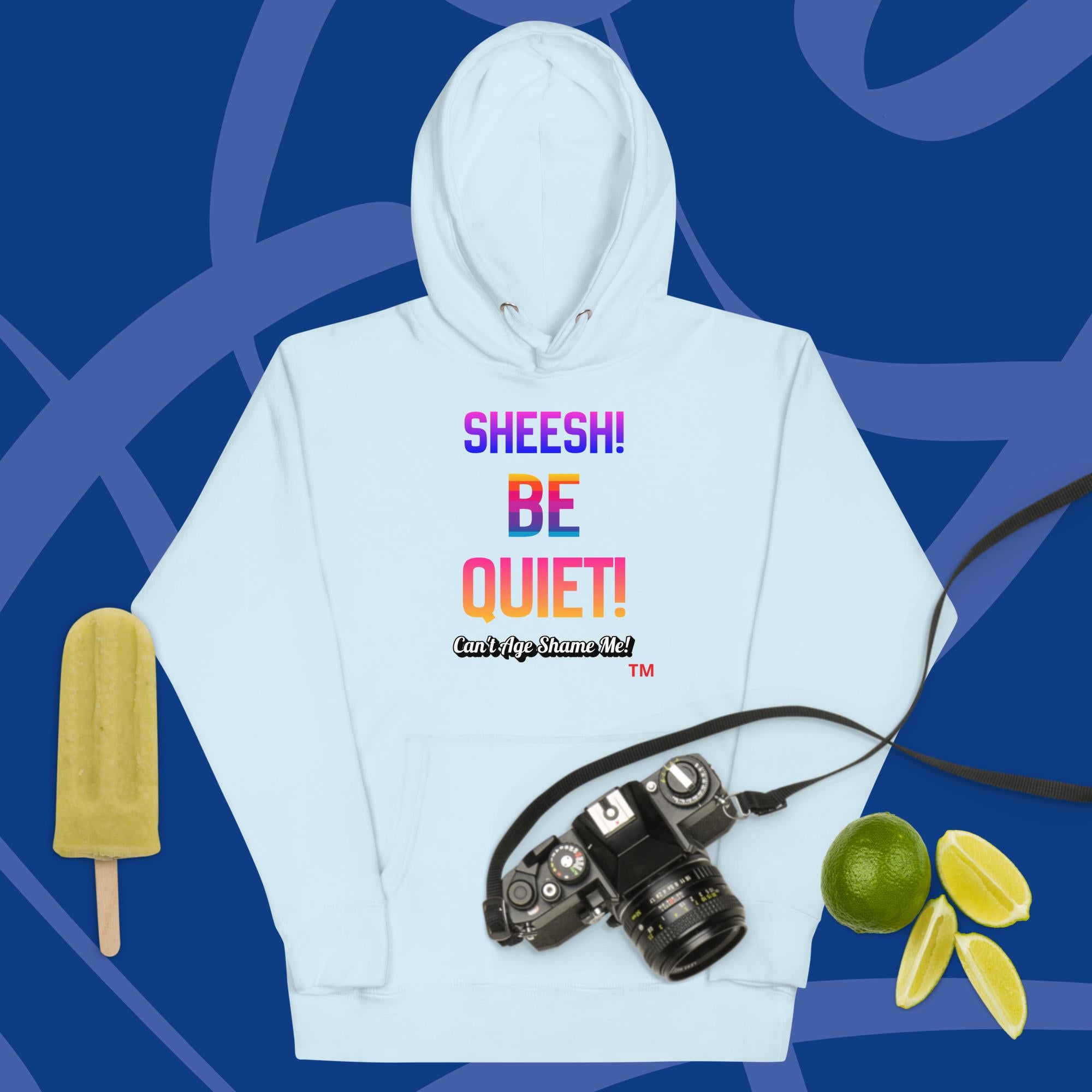 Sky Blue hoodie with colorful text: Sheesh! Be Quiet! 'Can't Age Shame Me!
 on a blue background with camera, popsicle, and limes.


