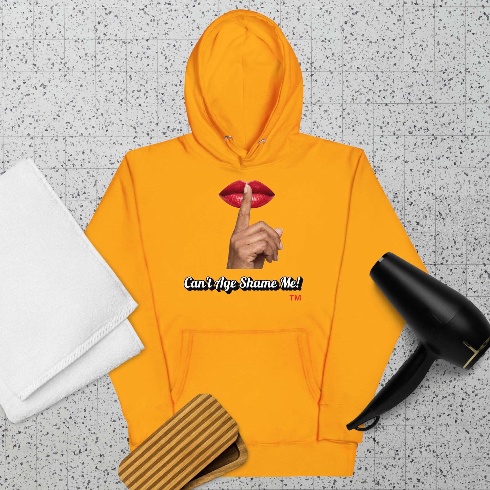 Gold hoodie with a graphic design of lips and a finger on a textured surface