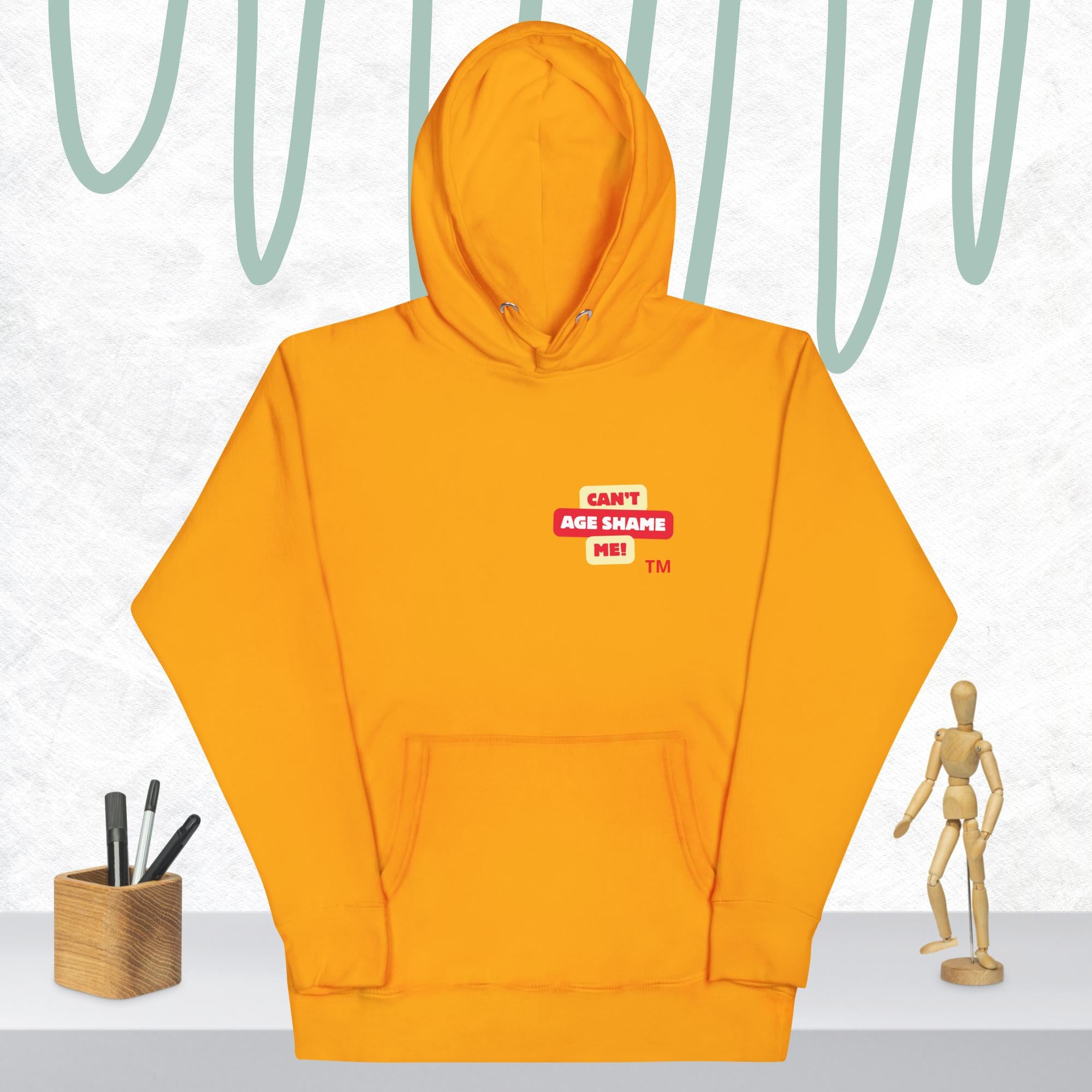 Team Gold hoodie with a red and white logo text 'CAN'T AGE SHAME ME! on a light gray background