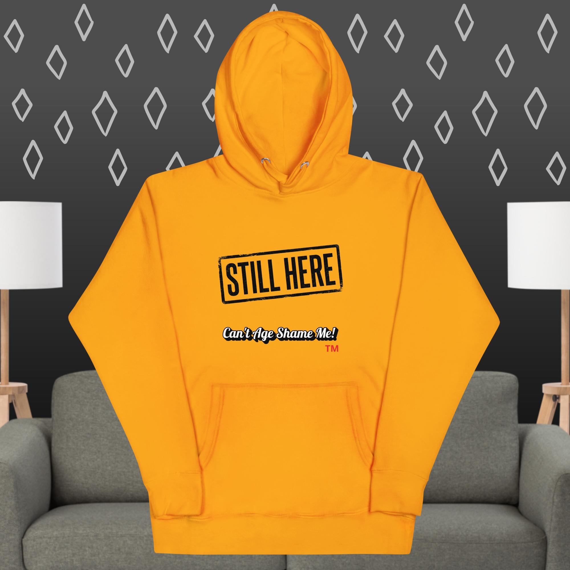 Yellow hoodie with text on a gray couch against a patterned wall.