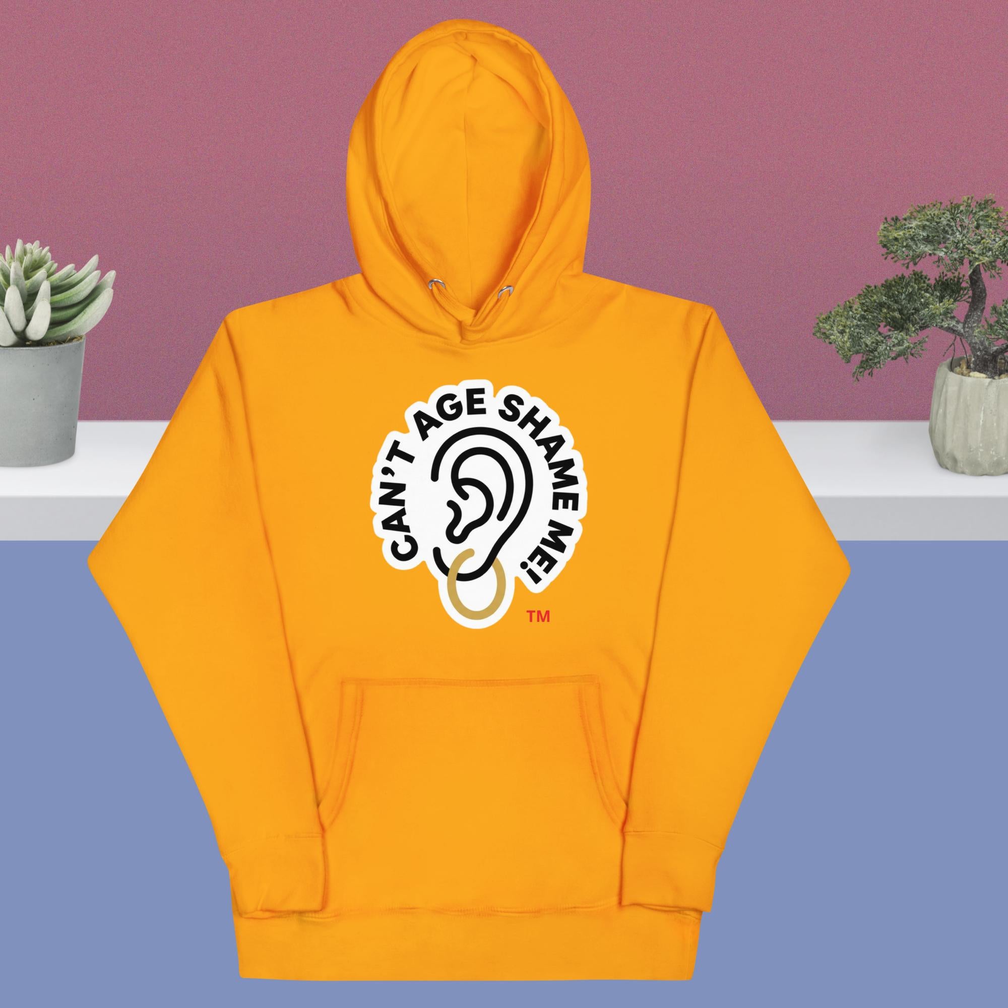 Team Gold hoodie with 'Can't Age Shame Me' logo on a purple and blue gradient background