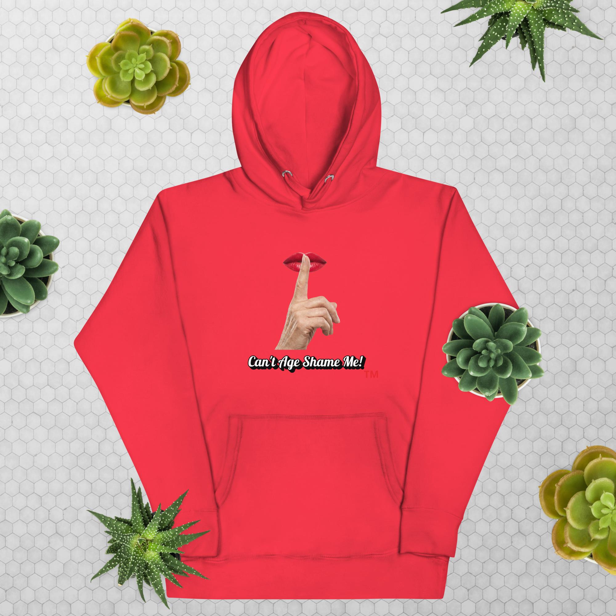 Team Red hoodie with graphic design and text, Can’t Age Shame Me!, on a patterned background with succulents