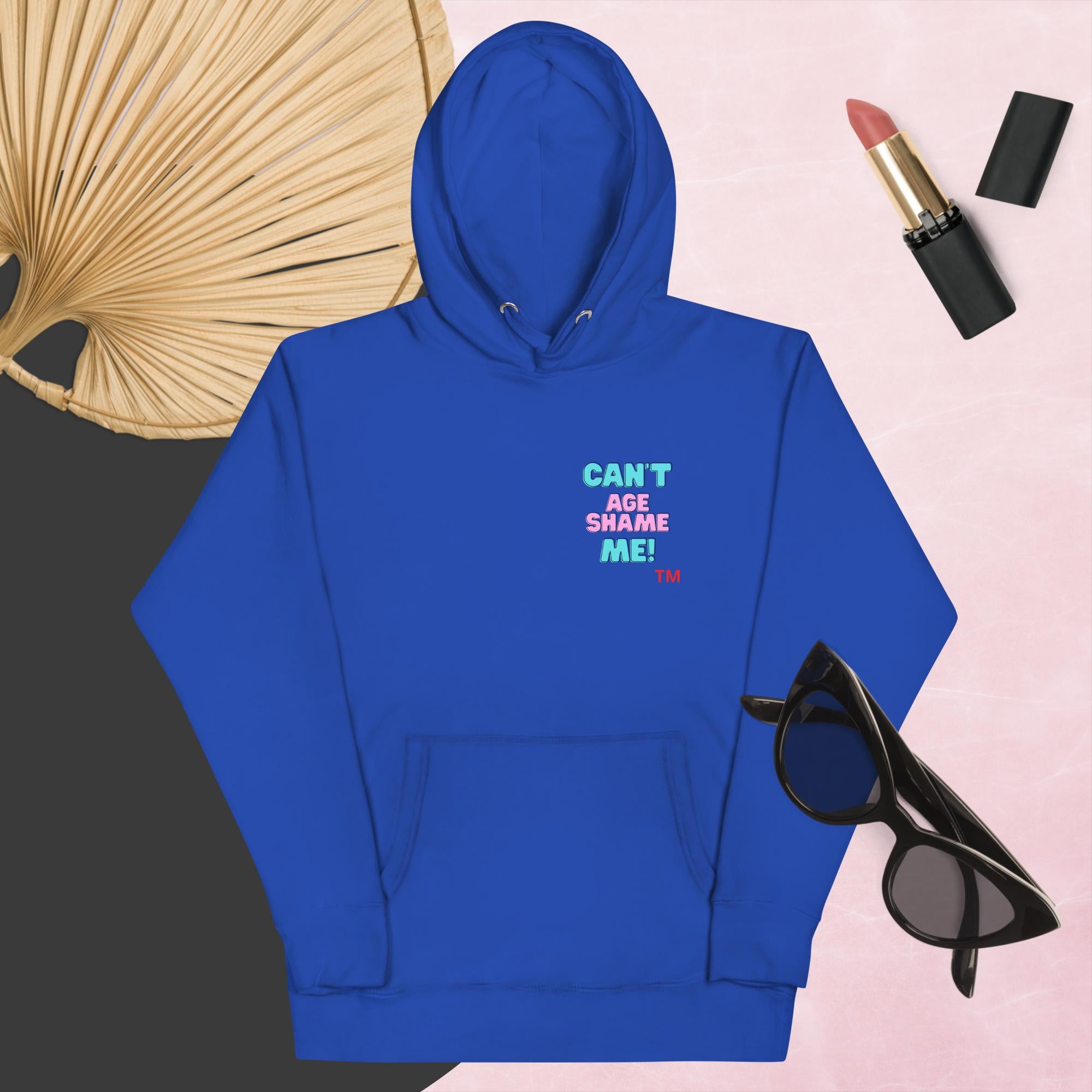 Tea Royal hoodie with text, 'Can't Age Shame Me' with sunglasses, lipstick, and a decorative leaf on a pink background