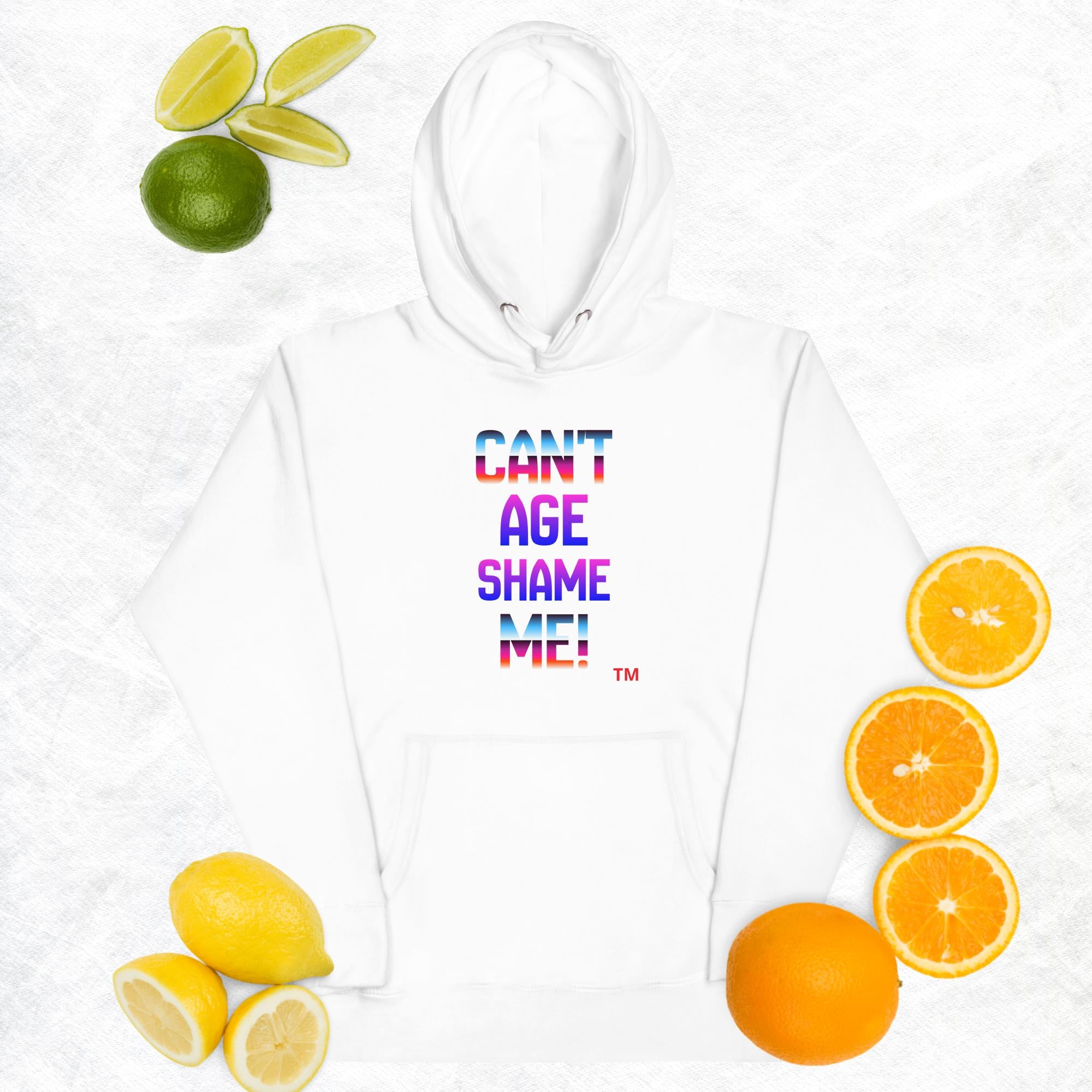 White hoodie with colorful text 'CAN'T AGE SHAME ME!' surrounded by fruits on a light gray background