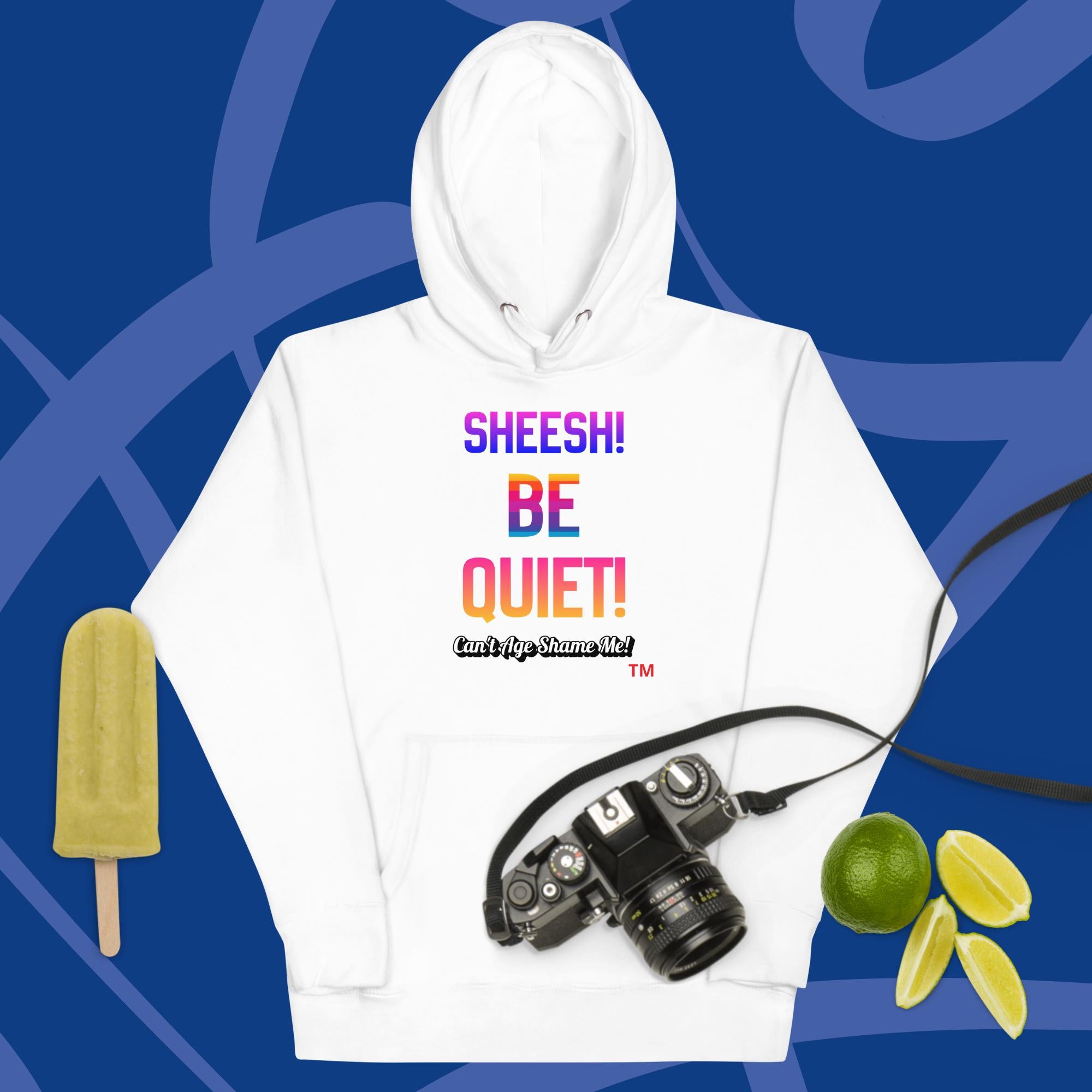White hoodie with colorful text: Sheesh! Be Quiet! 'Can't Age Shame Me!
 on a blue background with camera, popsicle, and limes.


