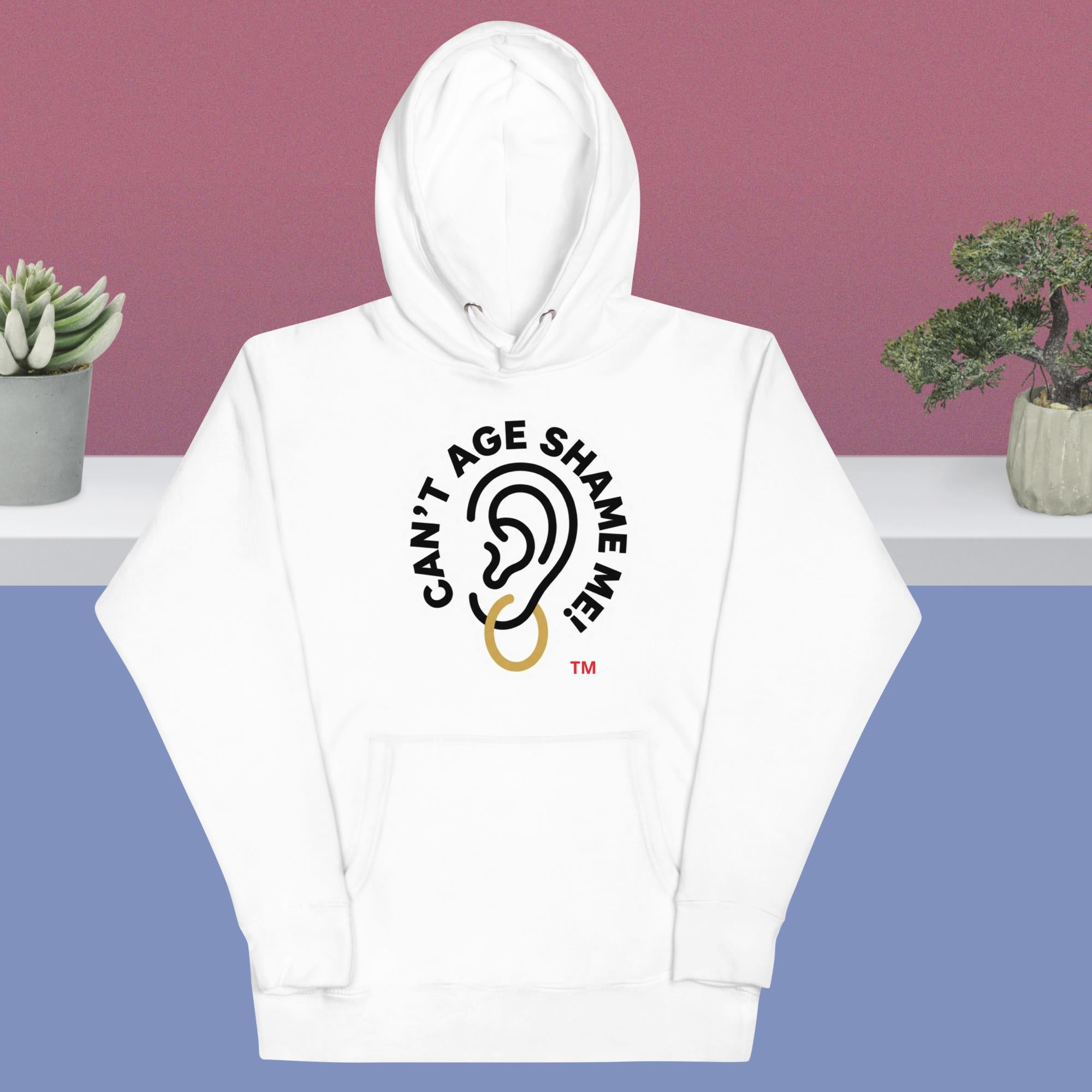 White hoodie with 'Can't Age Shame Me' design on a blue and pink gradient background