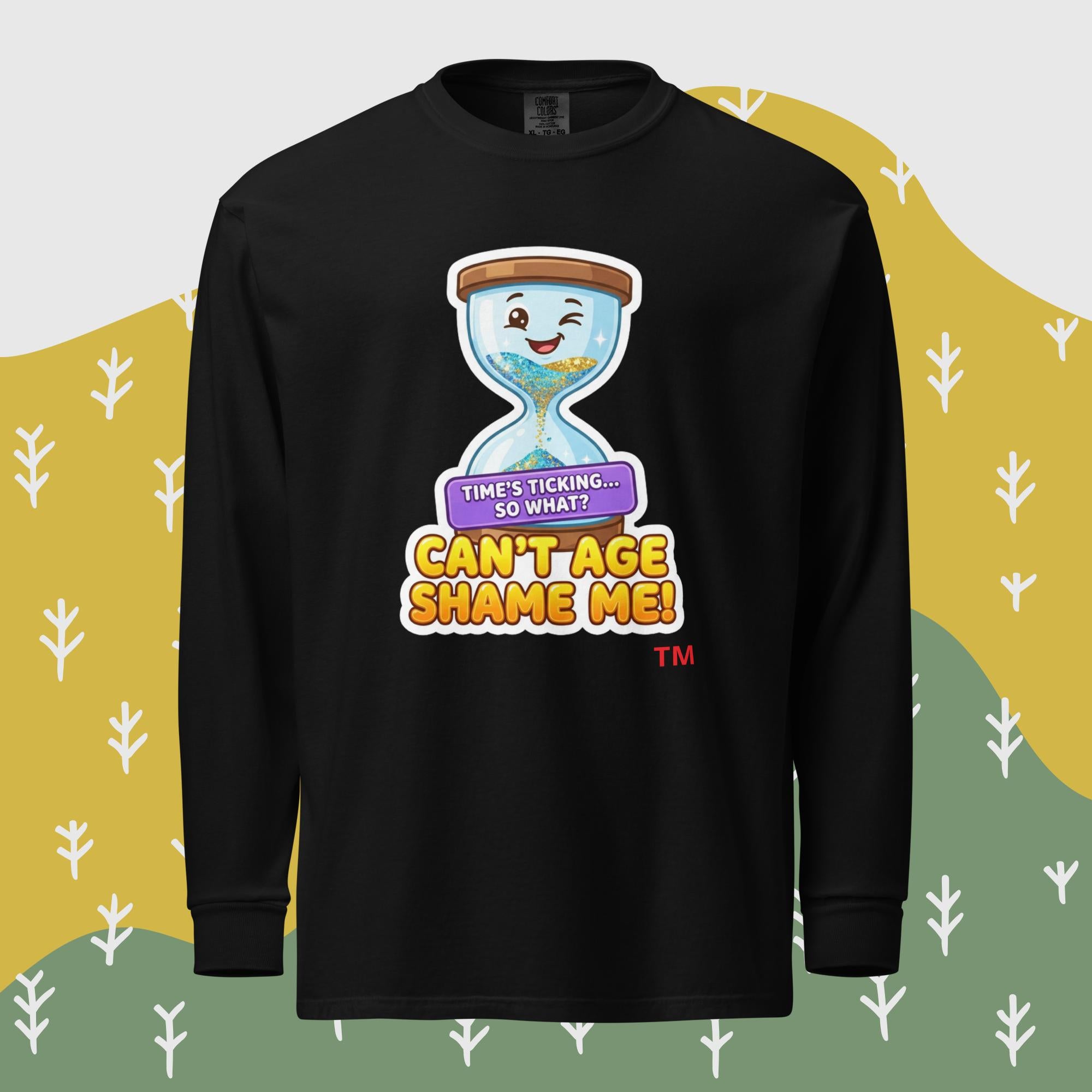 Black long-sleeve shirt with a cartoon hourglass design and text 'Can't Age Shame Me' graphic on a patterned background

