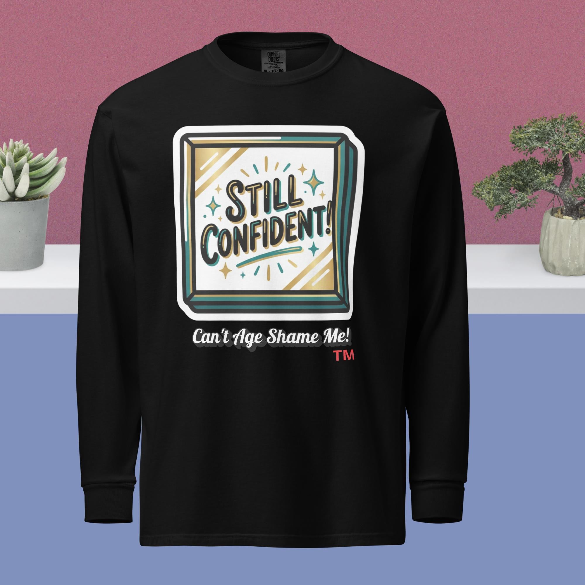 Black long-sleeve shirt with 'Still Confident! Can't Age Shame Me!' design on a blue and pink gradient background.