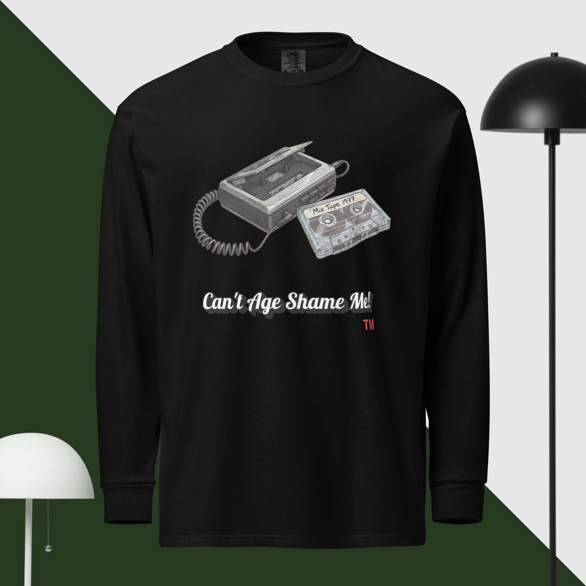 Black long-sleeve shirt with cassette tape design and text 'Can't Age Shame Me' on a green and white background.