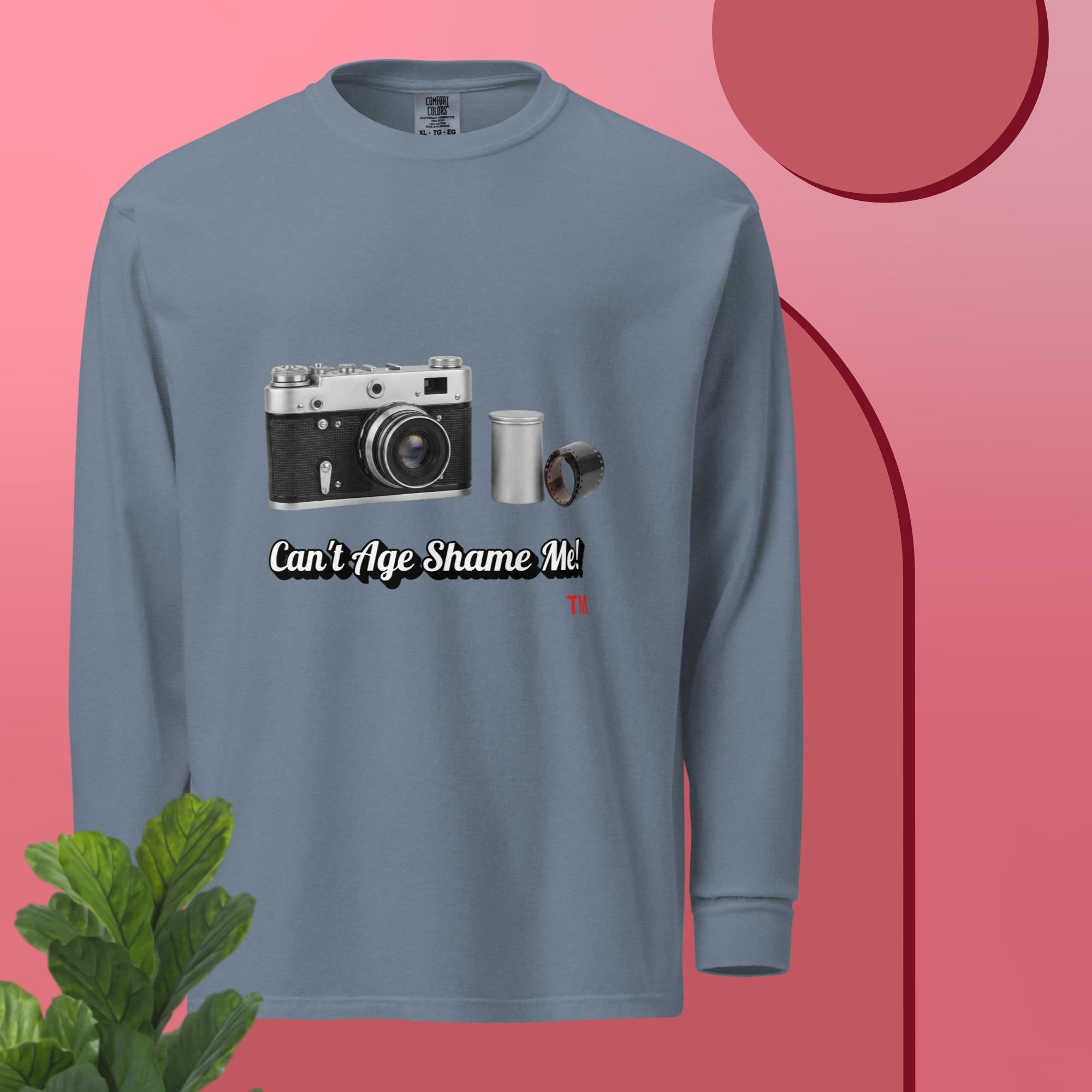 Blue jean long sleeve shirt with camera graphic and text  can't age shame me on a pink background