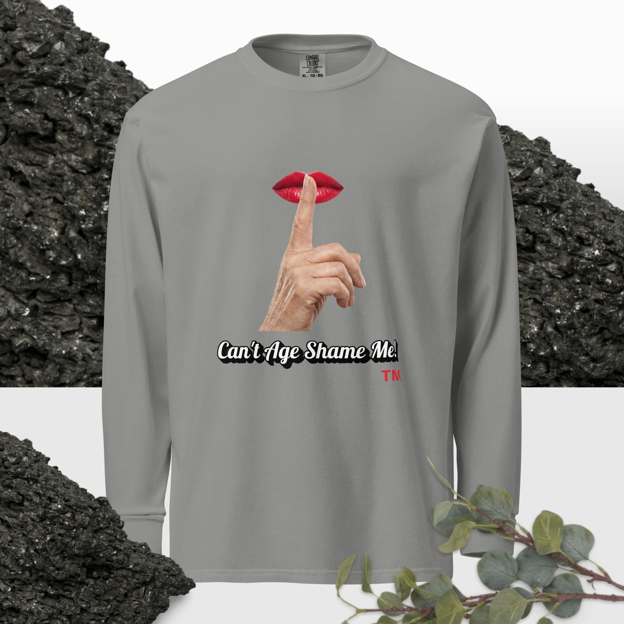 Gray long-sleeve shirt with graphic design of finger on mouth and text 'Can't Age Shame Me' on a textured background.