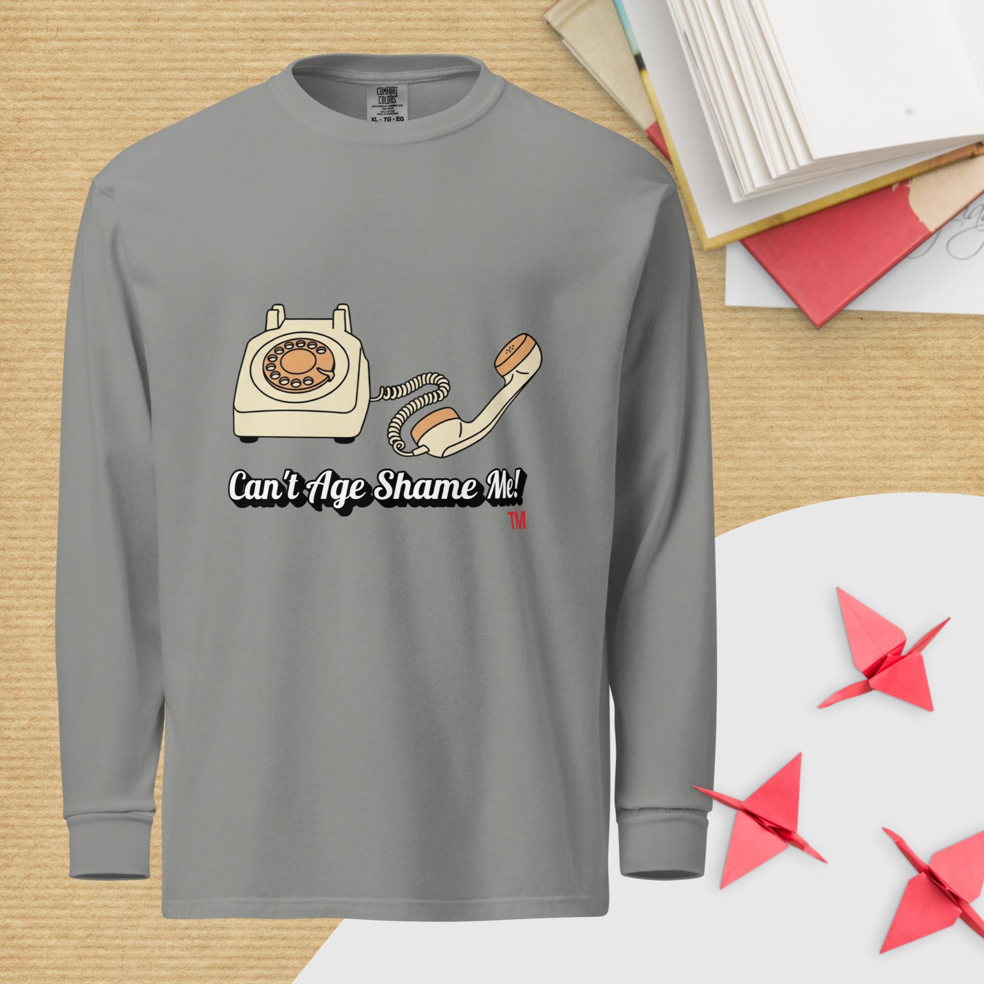 Gray long-sleeve shirt with a vintage phone graphic and text 'Can't Age Shame Me!' on a wooden surface.