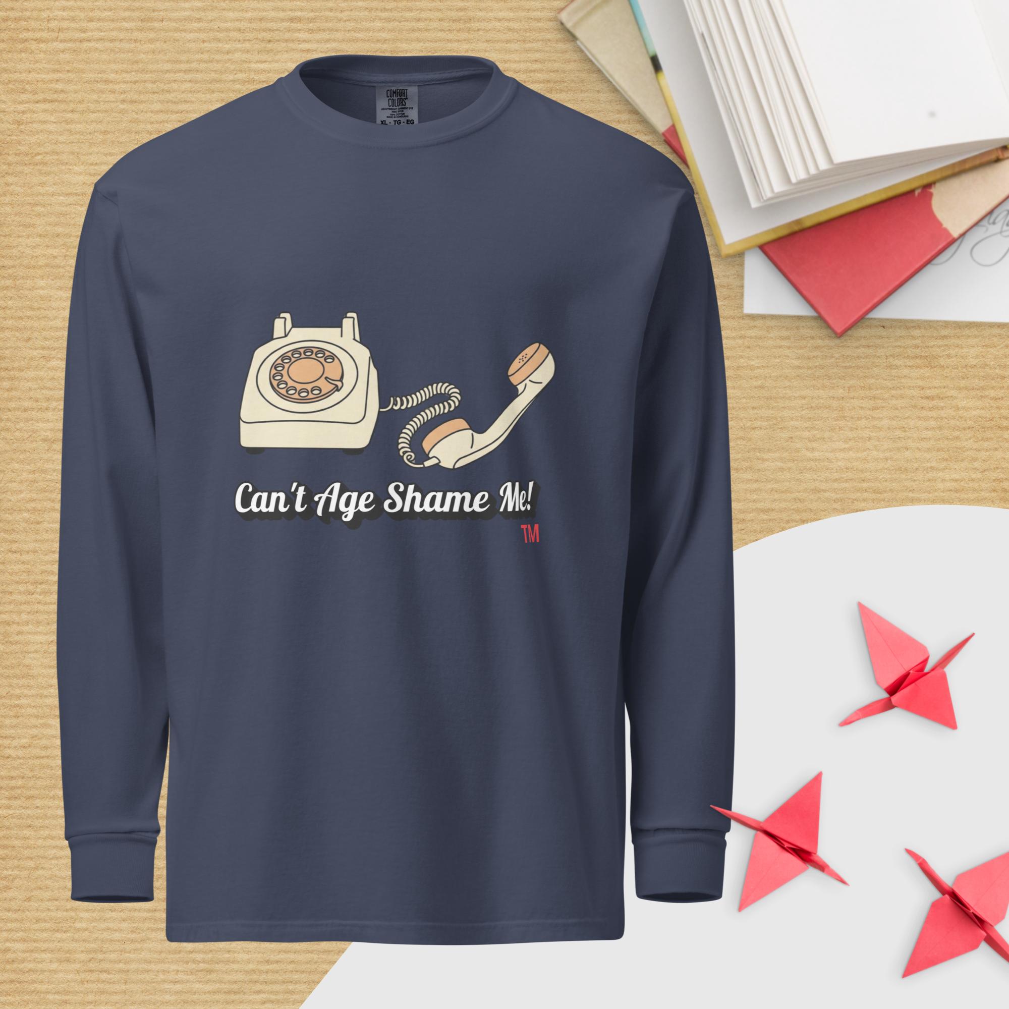 Navy blue long-sleeve shirt with a graphic of an old telephone and text 'Can't Age Shame Me!' on a wooden surface.
