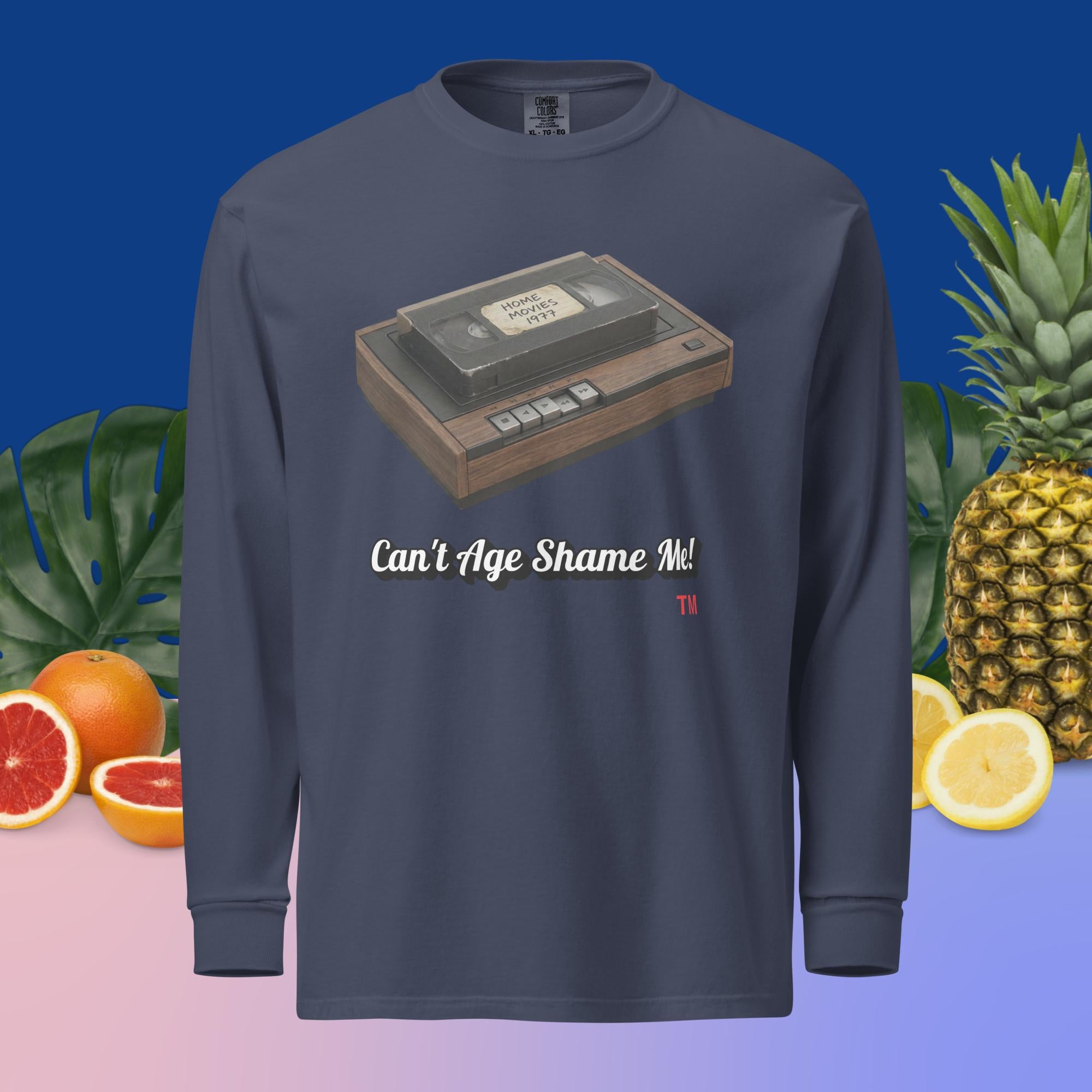 navy long-sleeve shirt with a VHS tape design and text can't age shame me, surrounded by fruits and plants.