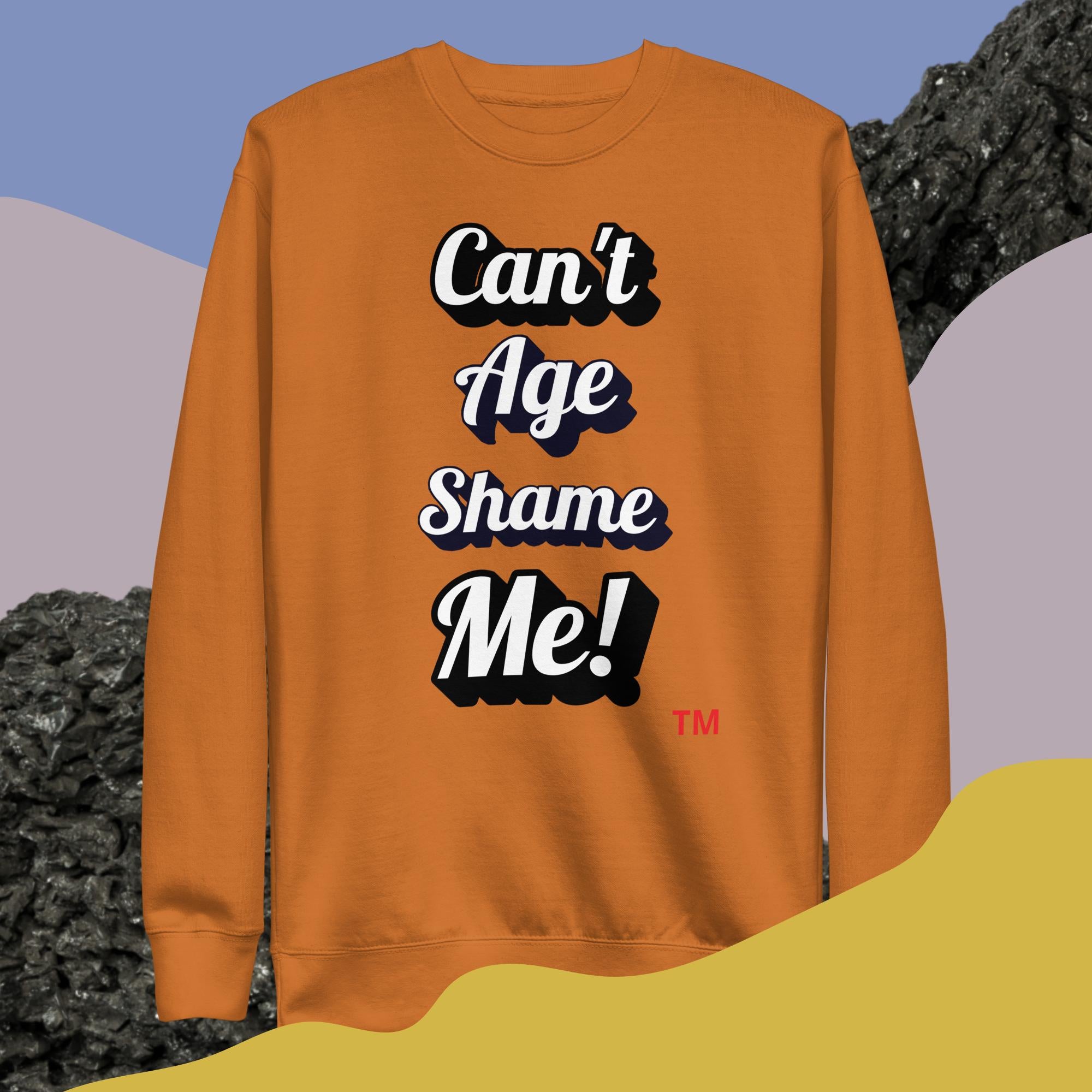 Orange sweatshirt with 'Can't Age Shame Me!' text on a colorful background