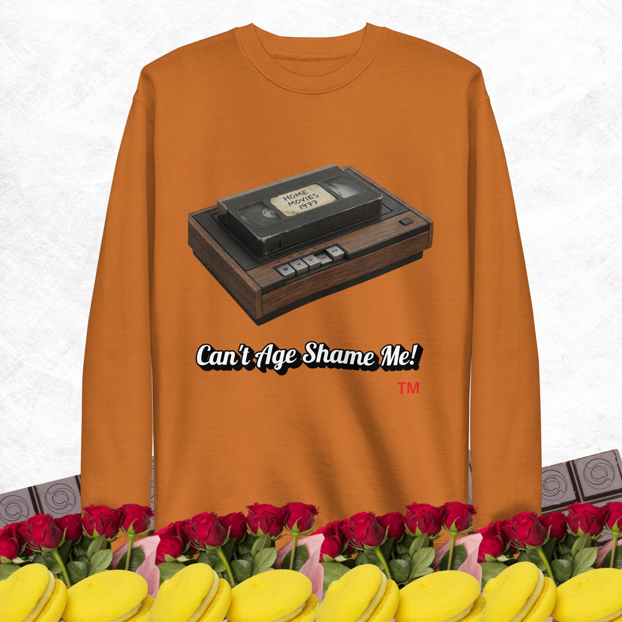 adobe long-sleeve shirt with a VHS tape graphic and text 'Can't Age Shame Me!' on a white background.