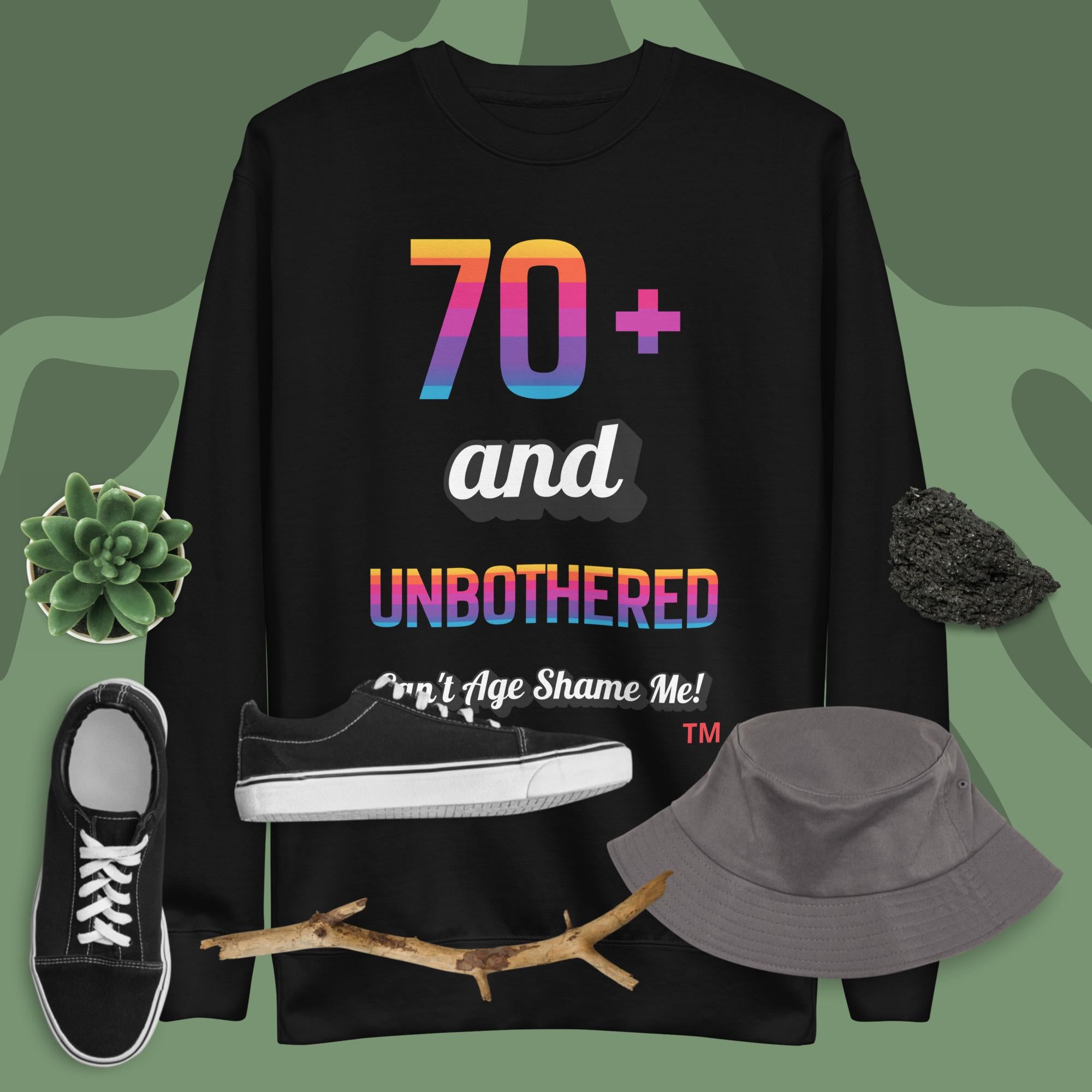 Black sweatshirt with colorful text, black sneakers, gray hat, and branch on a green background