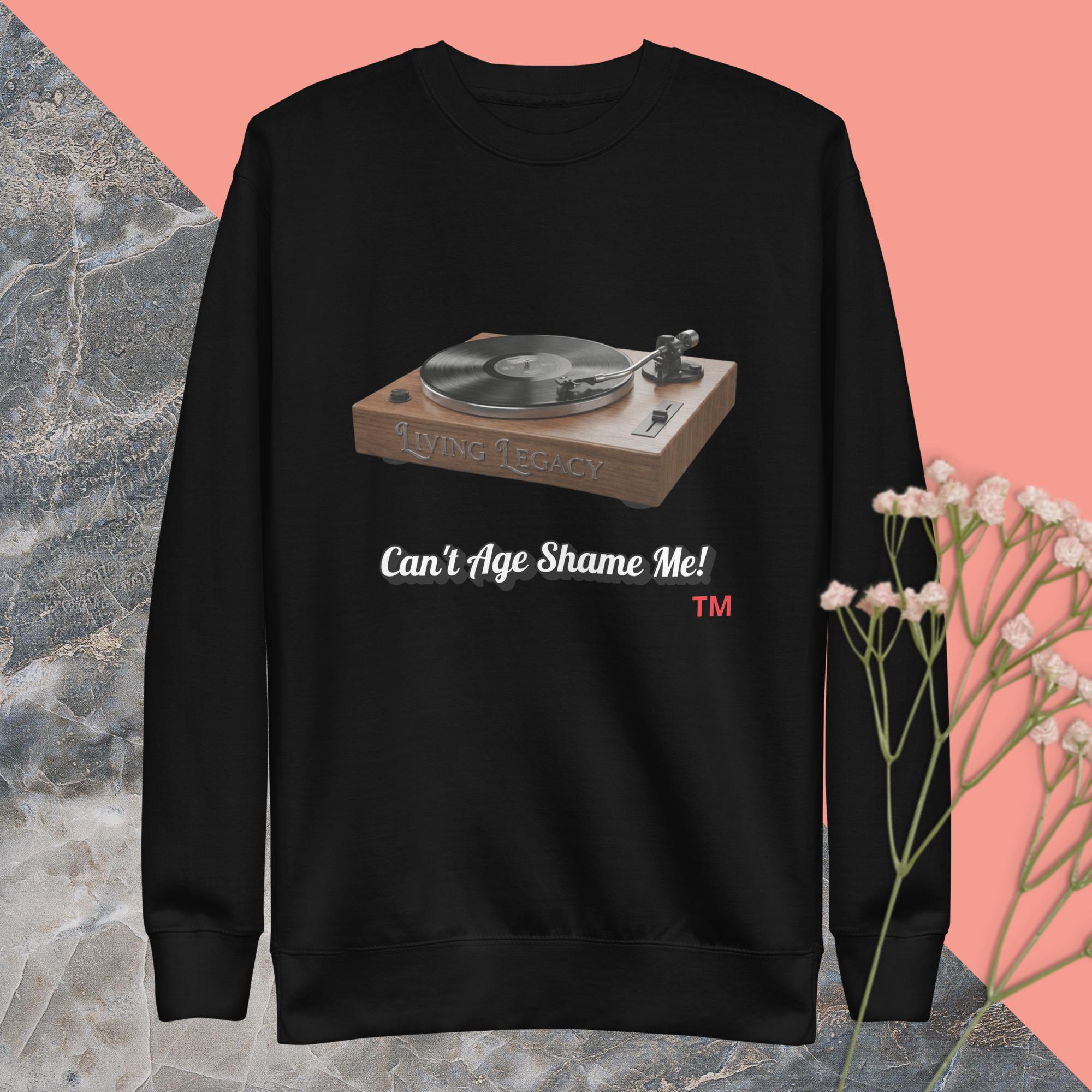 black sweatshirt with a record player graphic and text can't age shame me ! on a pink and gray background