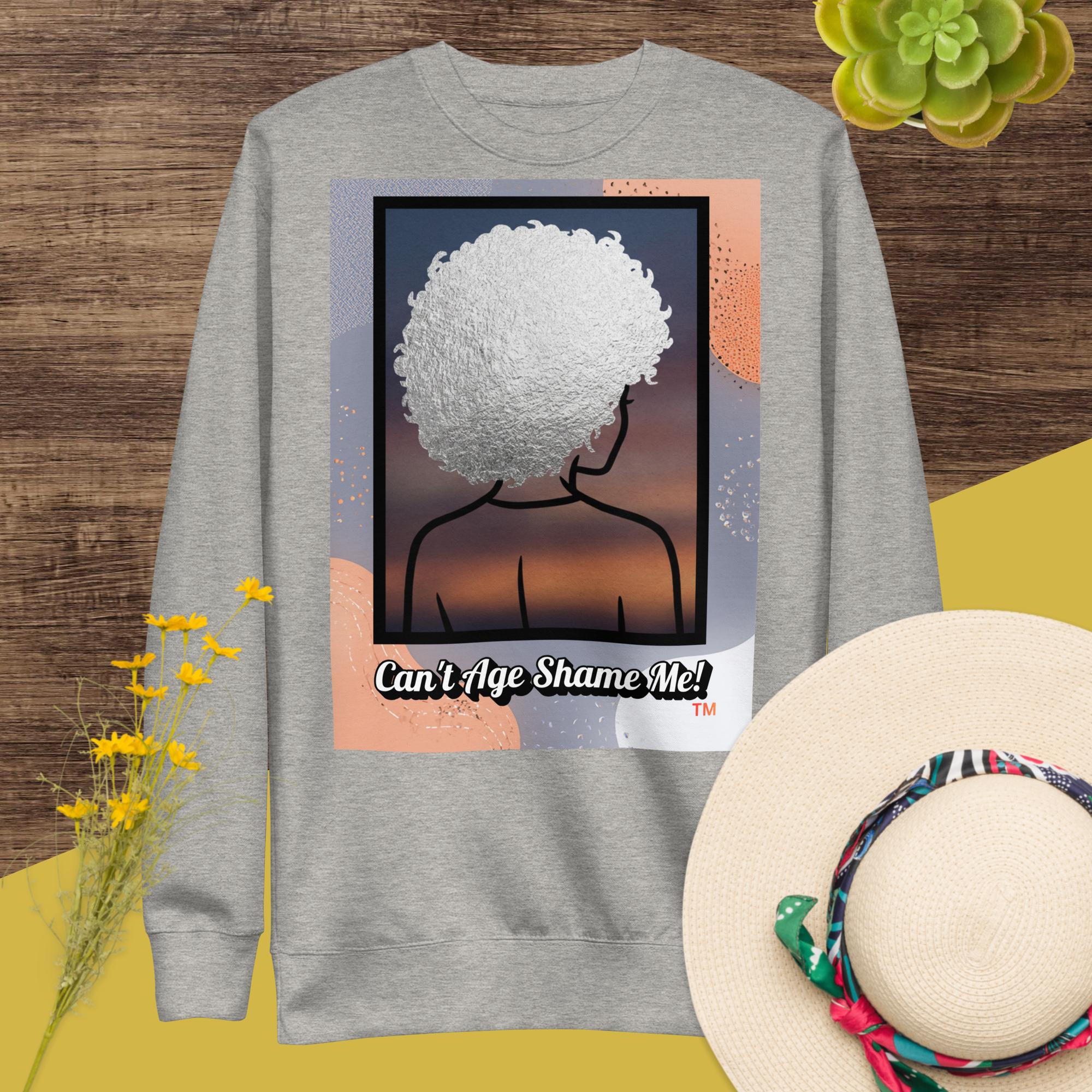 Gray sweatshirt with a graphic design of a person with textured hair and text 'Can't Age Shame Me!' on a colorful background.