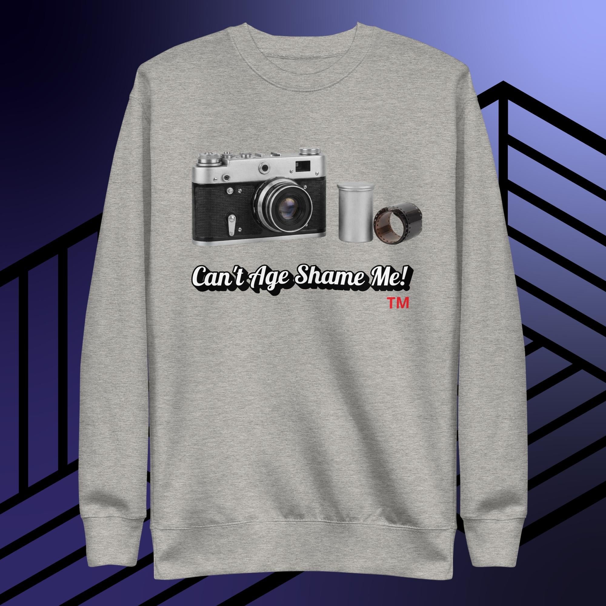 Gray sweatshirt with camera graphic and text 'Can't Age Shame Me!' on a blue and black striped background