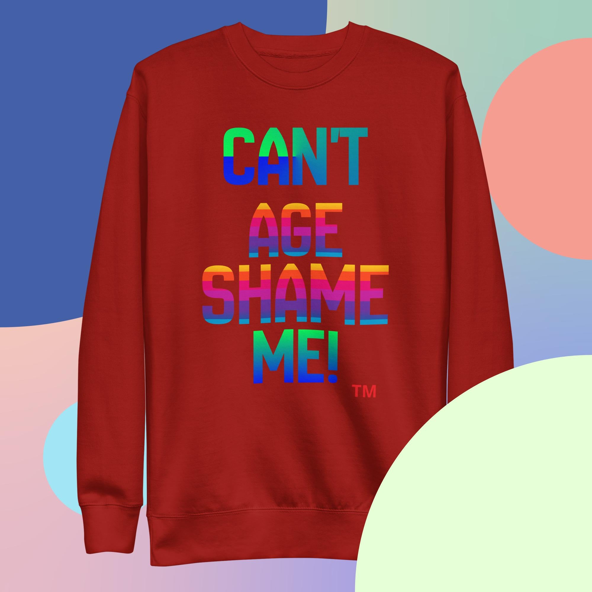 Red sweatshirt with colorful text 'CAN'T AGE SHAME ME!' on a multicolored background