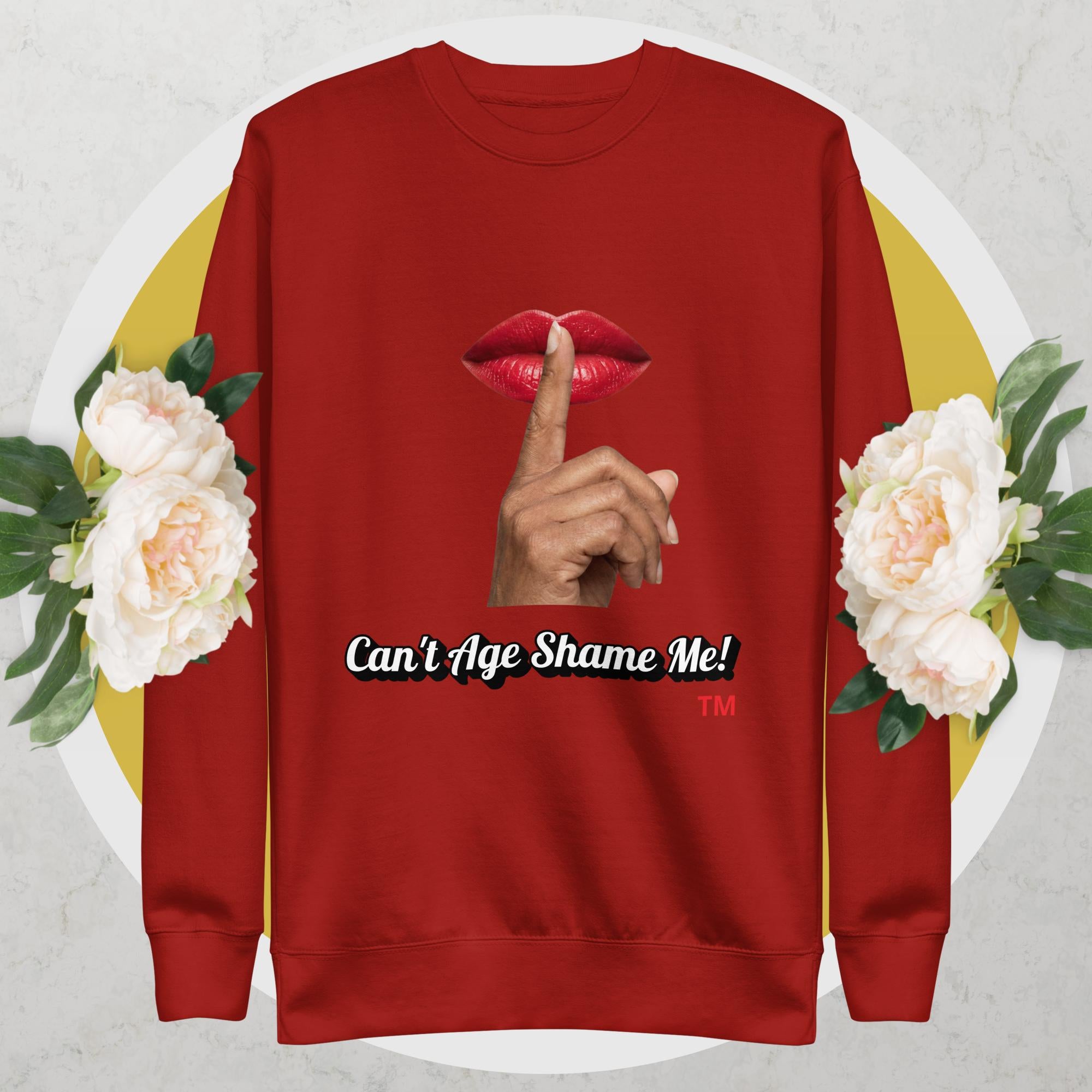 Red sweatshirt with graphic design of a hand, lips, and text 'Can't Age Shame Me!' on a floral background.