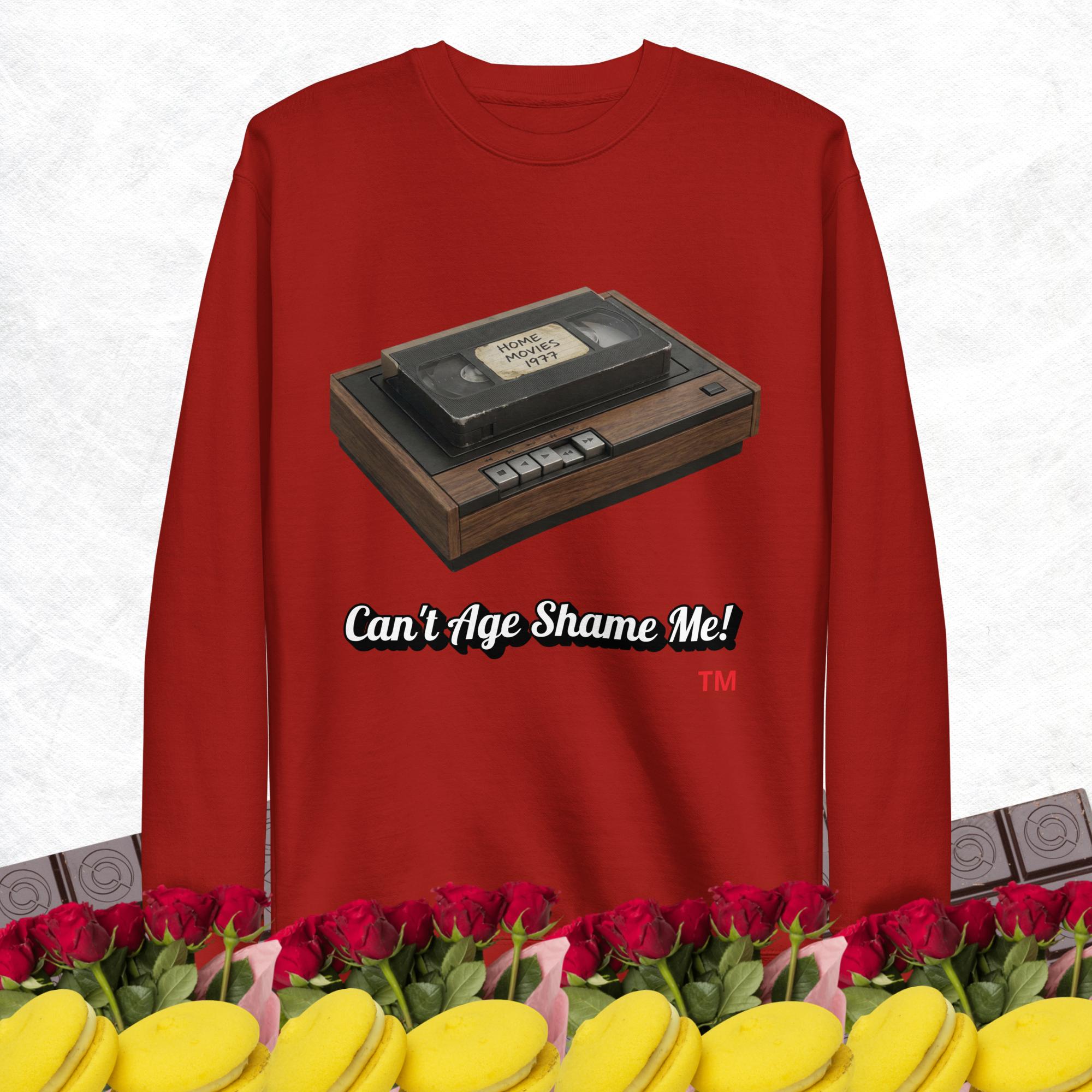 Red sweatshirt with a vintage VHS player graphic and text 'Can't Age Shame Me!' on a white background.