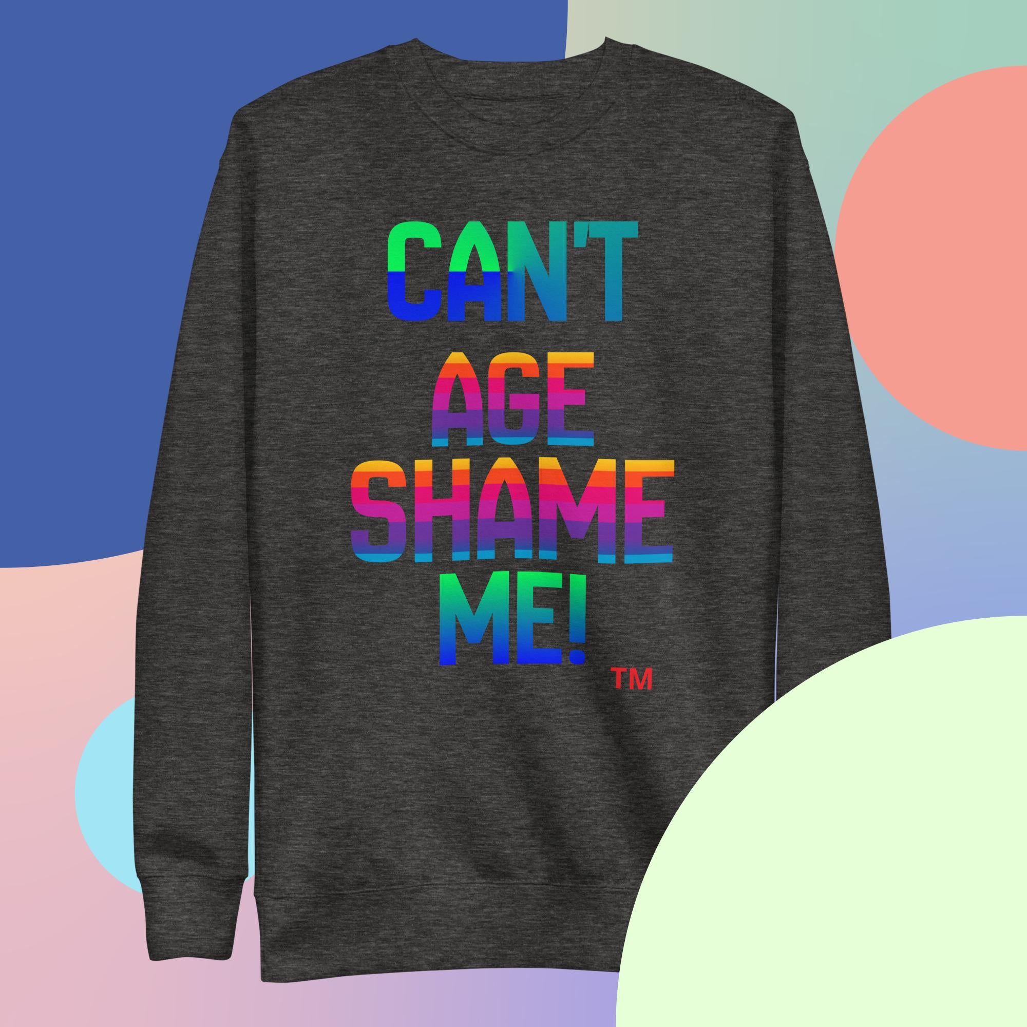 Dark gray sweatshirt with colorful text 'CAN'T AGE SHAME ME!' on a multicolored background