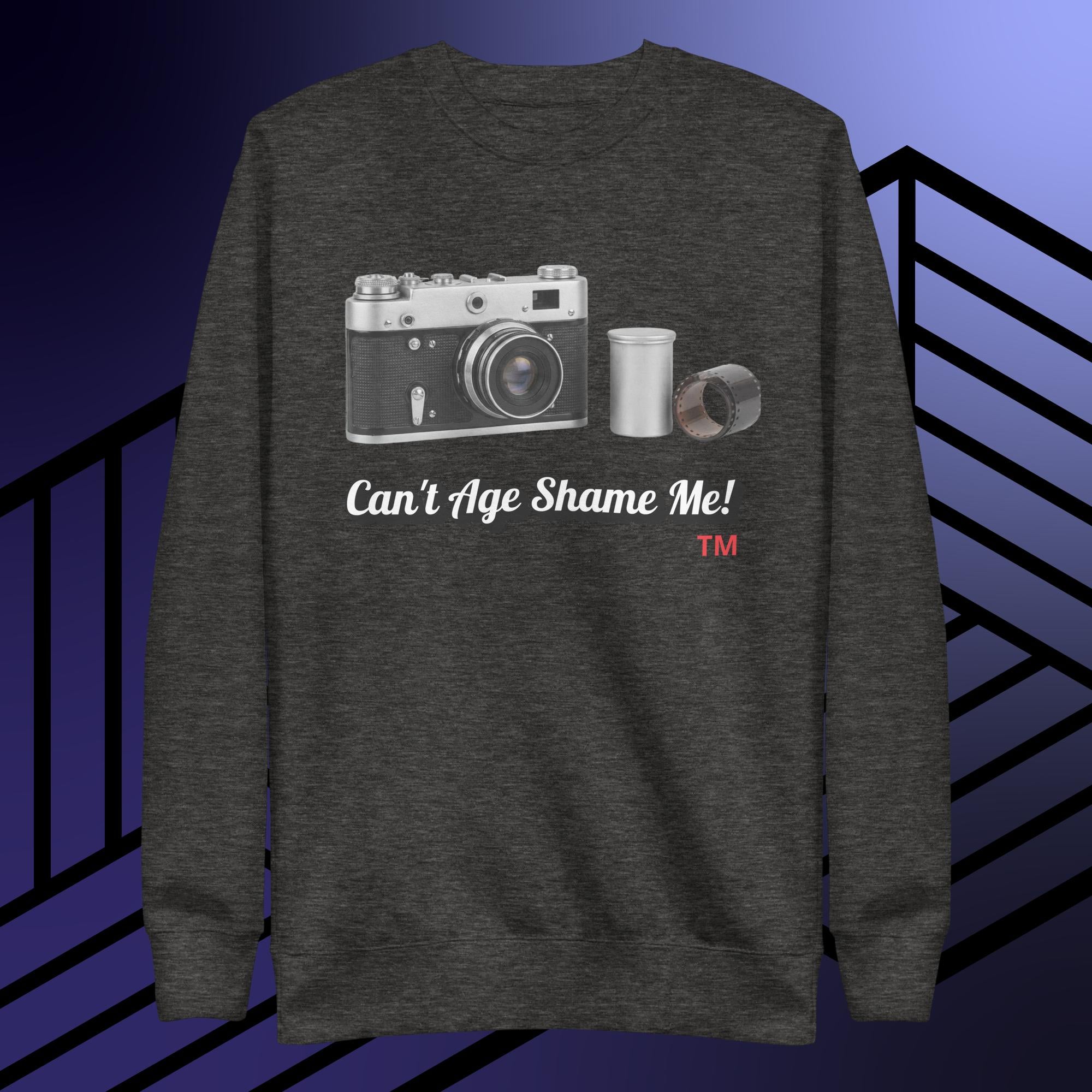 charcoal gray sweatshirt with camera graphic and text can't age shame me! on a blue and black striped background.