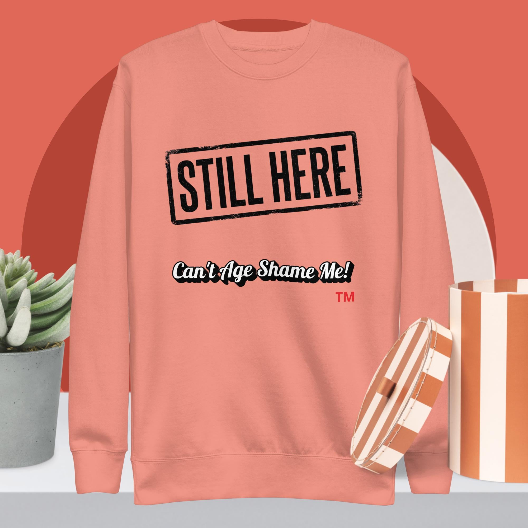 Dusty Rose sweatshirt with 'STILL HERE Can't Age Shame Me!' text on a red background