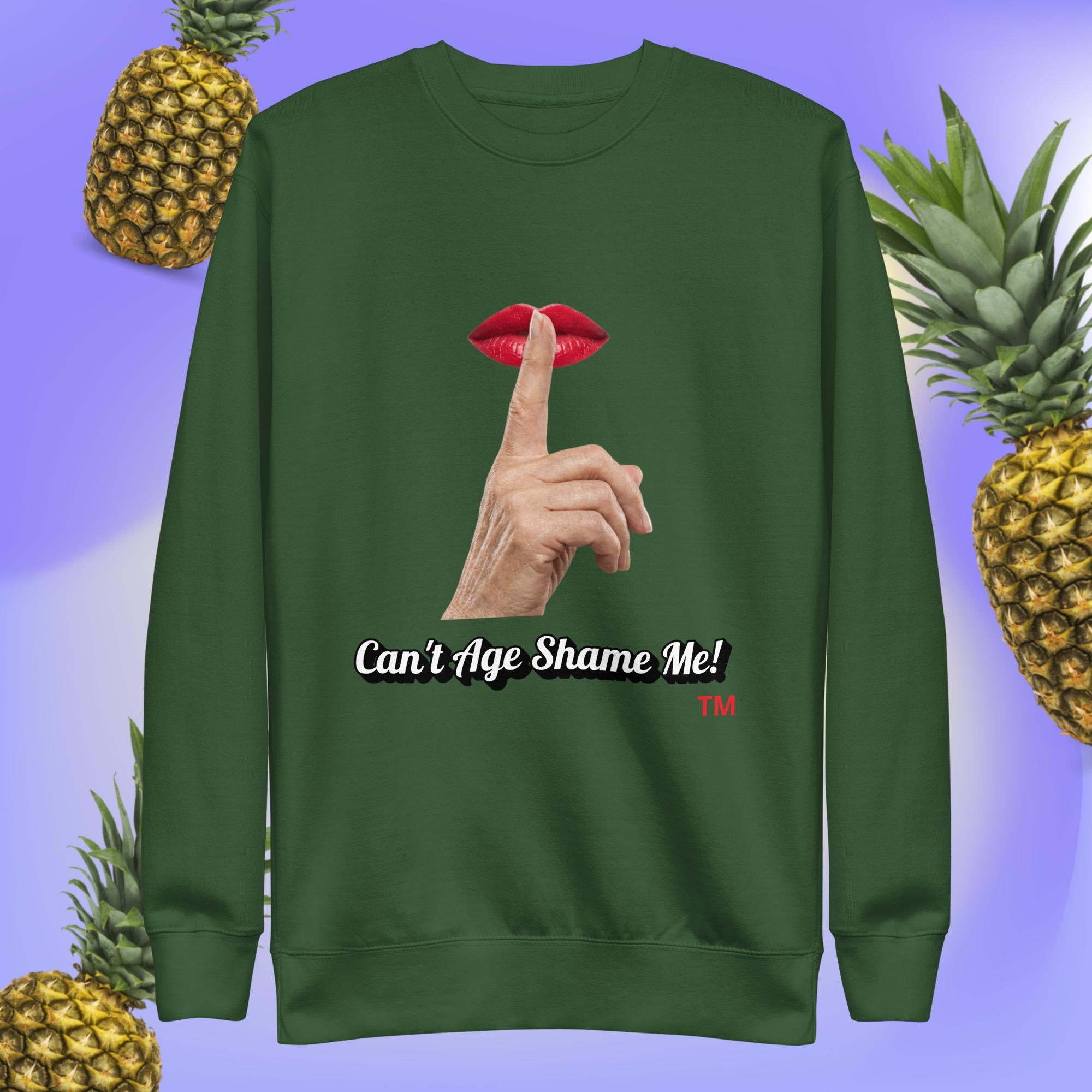 Forest Green sweatshirt with a graphic design of finger on mouth and text 'Can't Age Shame Me!' on a blue background with pineapples.