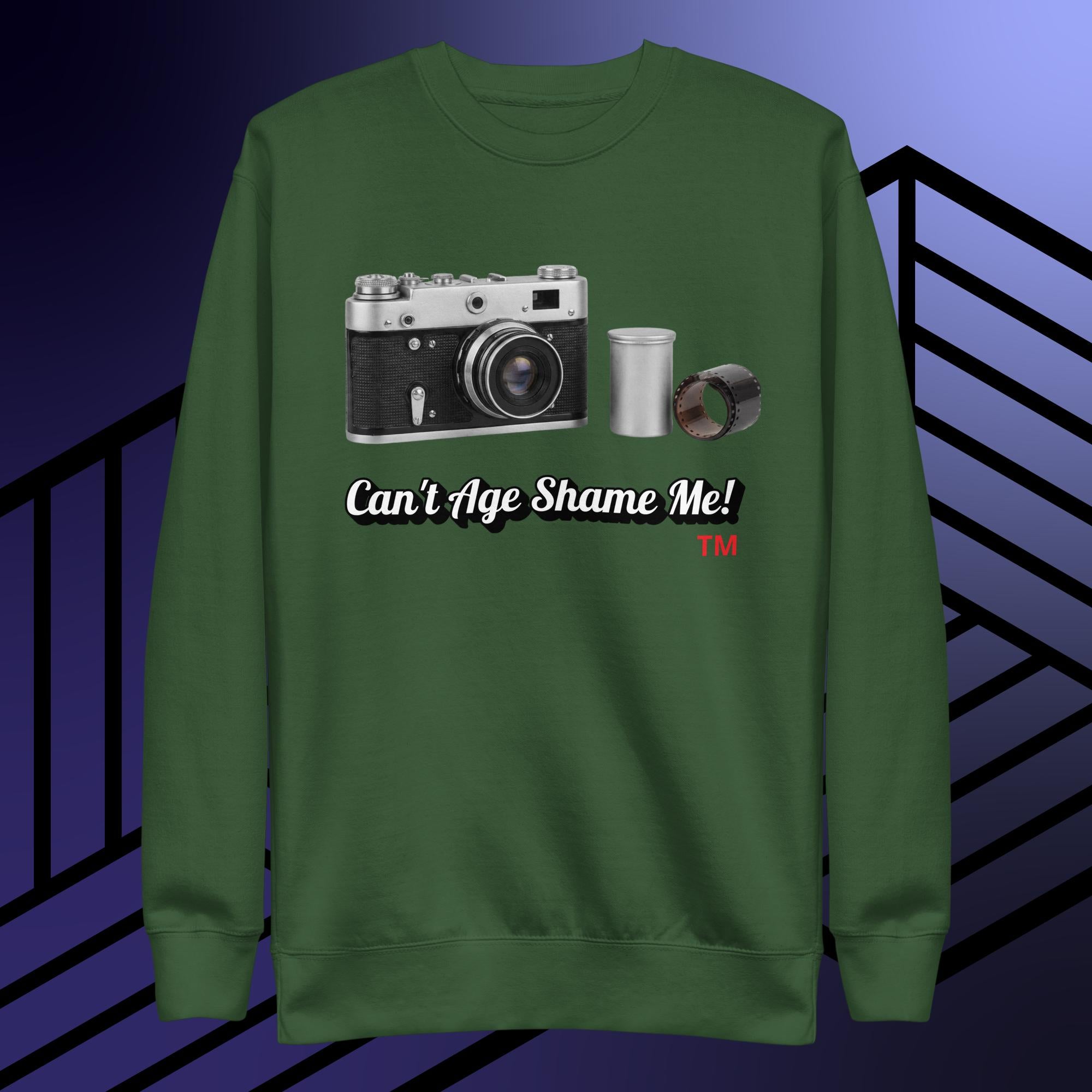 Green sweatshirt with camera graphic and text 'Can't Age Shame Me!' on a blue and black striped background