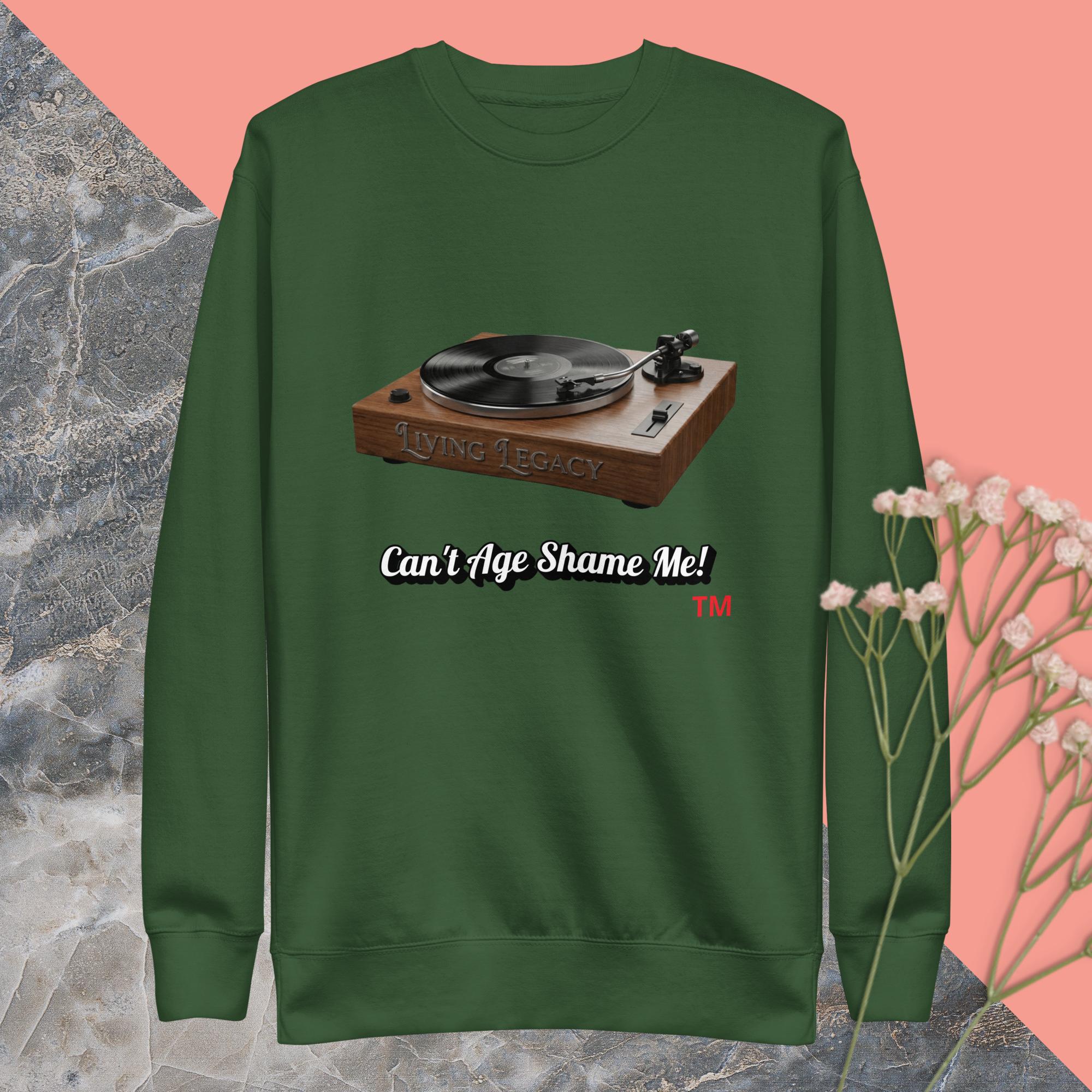 green  sweatshirt with a record player graphic and text can't age shame me ! on a pink and gray background