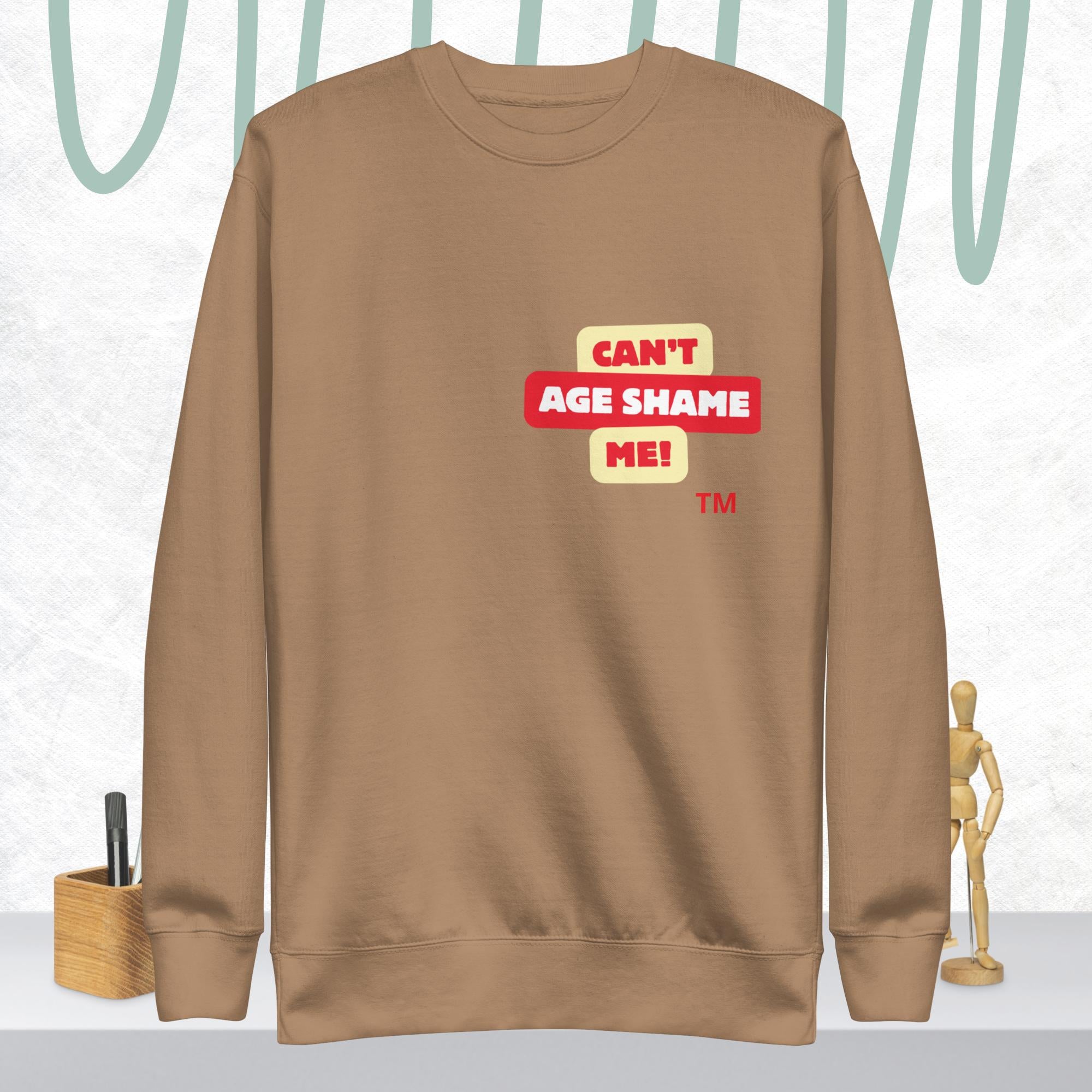 Latte sweatshirt with 'CAN'T AGE SHAME ME!' text logo on a light gray background